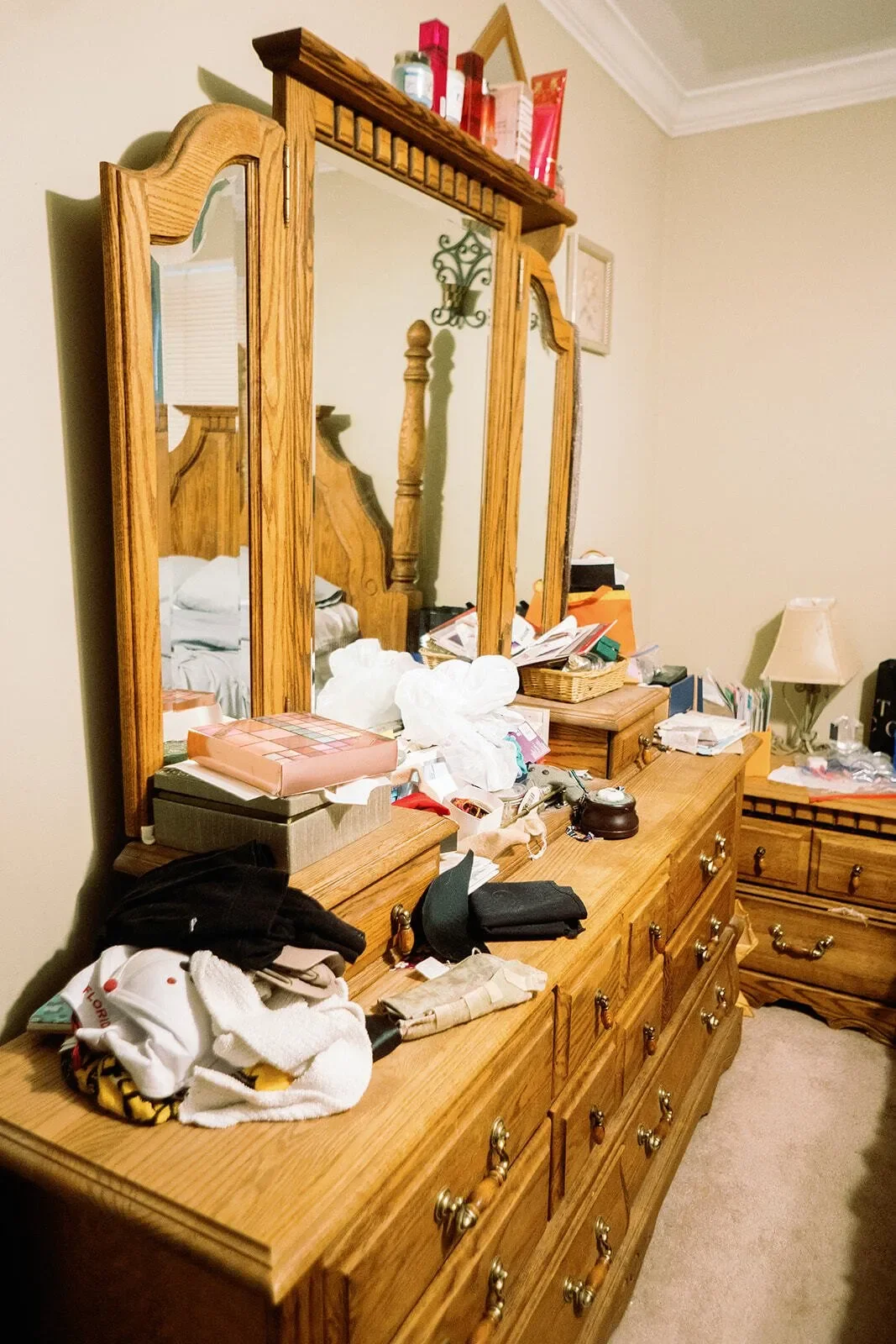 Before of the dresser with lots of clothes and items on top