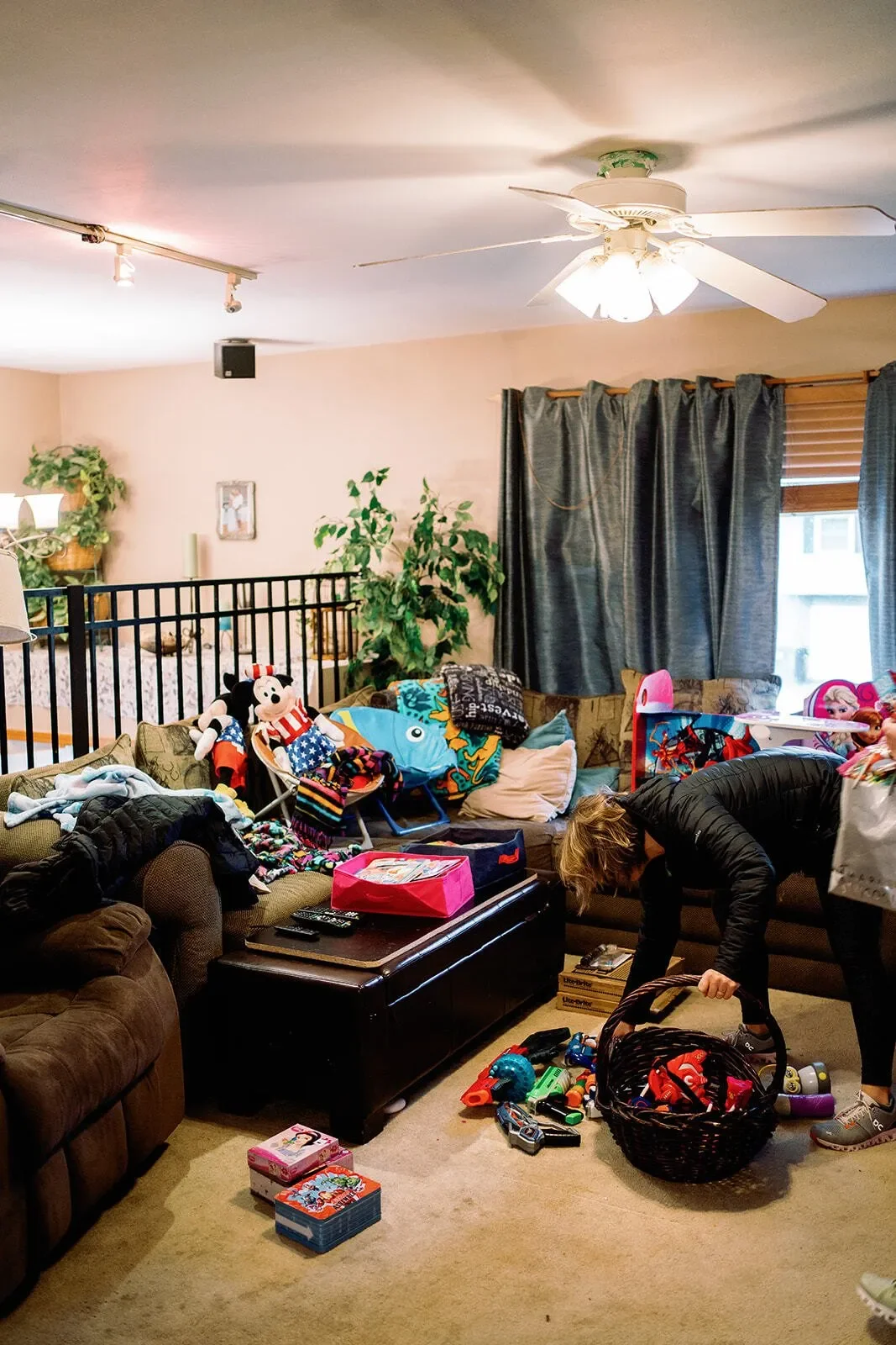 Before of the living room with toys and items on the floor and grey couch