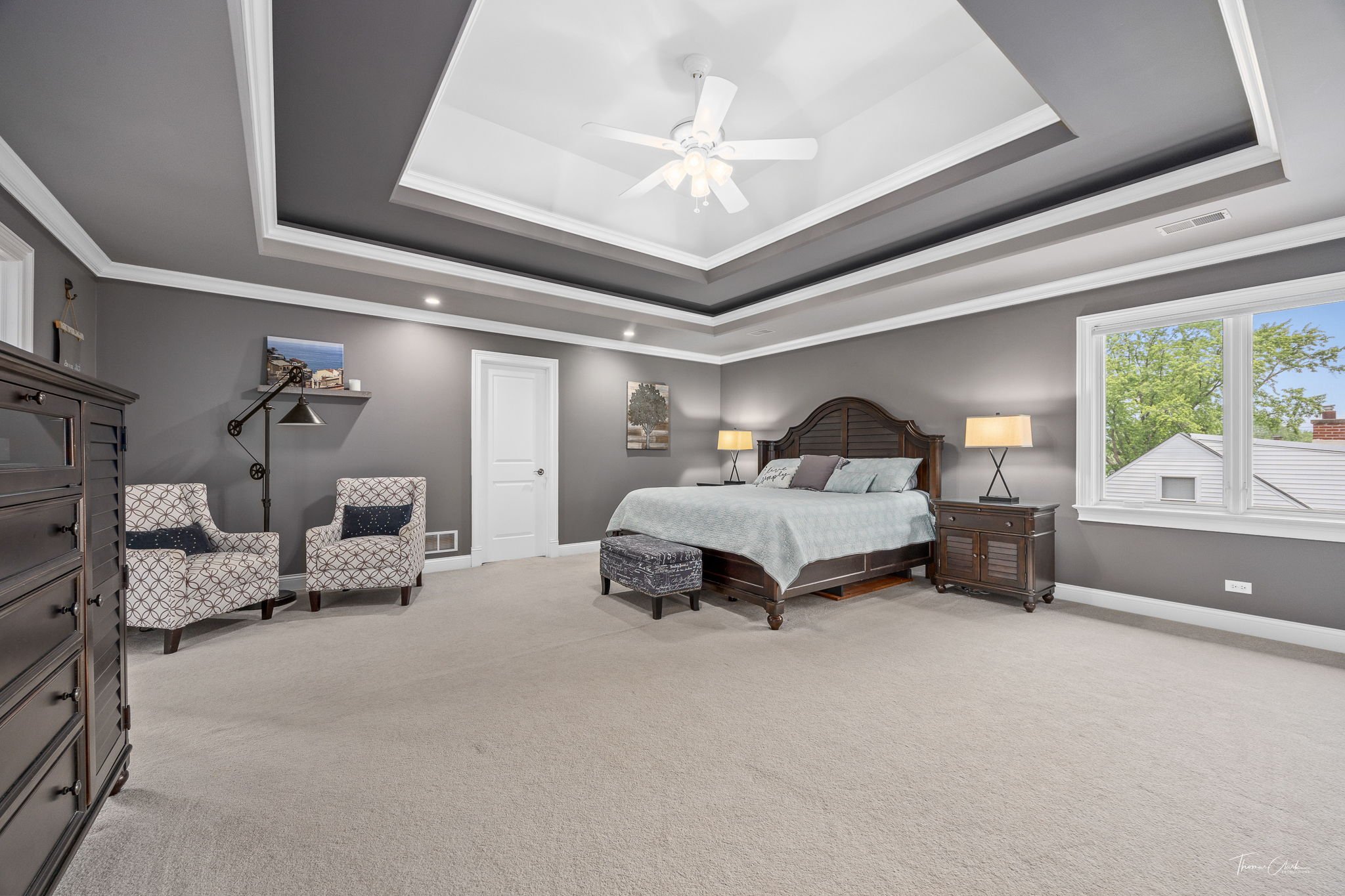 pacious staged master bedroom with a king-size bed, crisp white linens, and large windows.