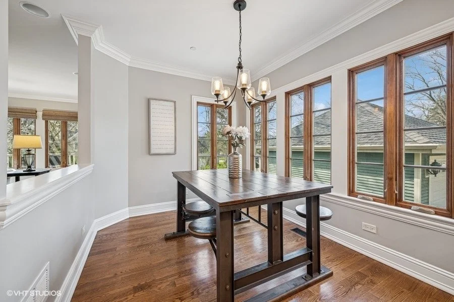 A formal dining room staged with a wooden table, upholstered chairs, and a simple floral centerpiece.