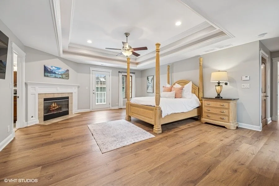 Airy staged bedroom featuring white bedding, a beige textured duvet, and symmetrical nightstands with white lamps.