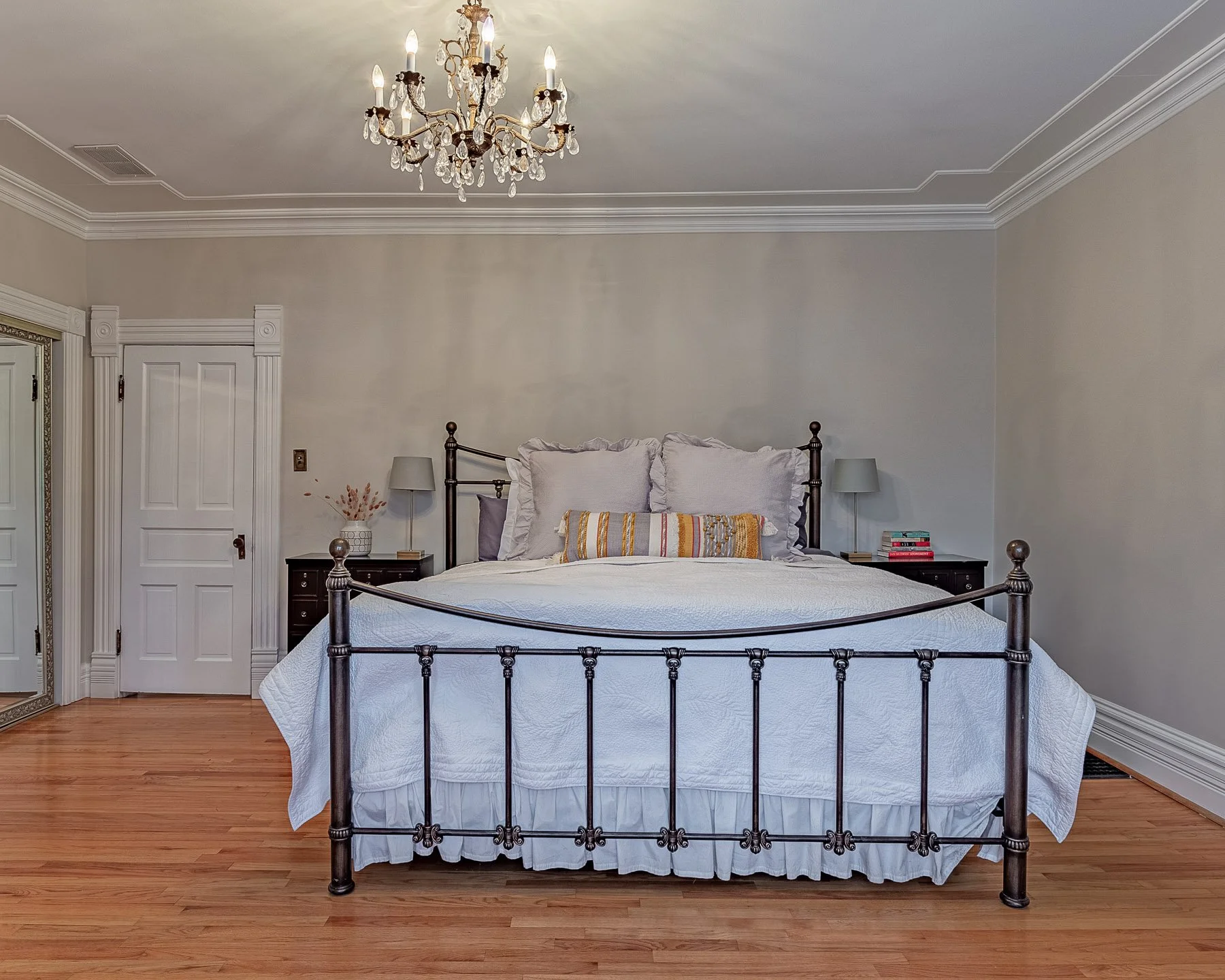 A staged bedroom with a bed and neutral accessories.