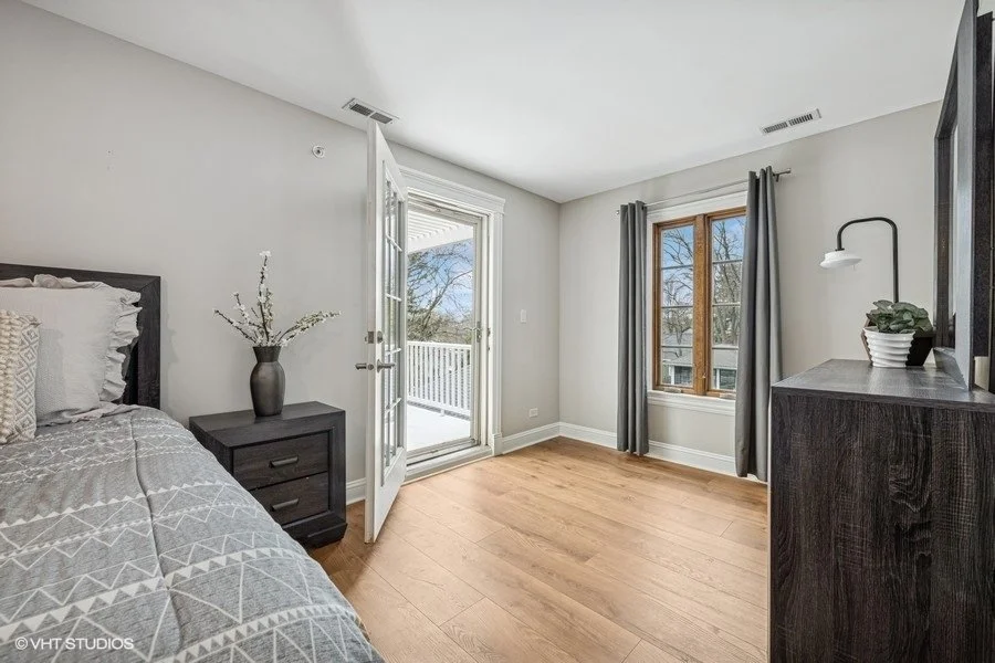 Staged guest bedroom with a bed, neutral linens, and simple decor, highlighting a functional and inviting space.