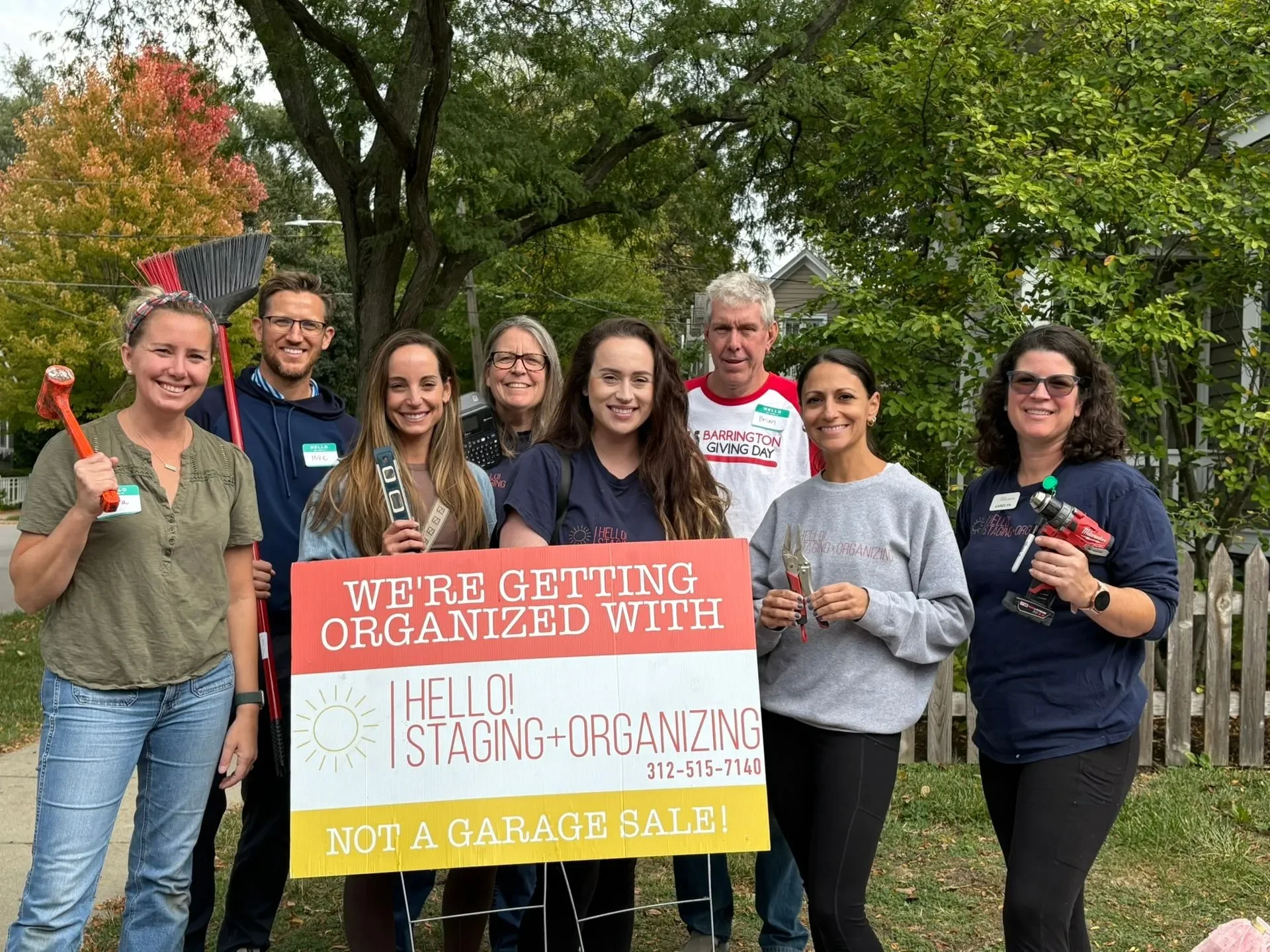 The team on a sidewalk with tools and a Hello! Staging and Organizing sign