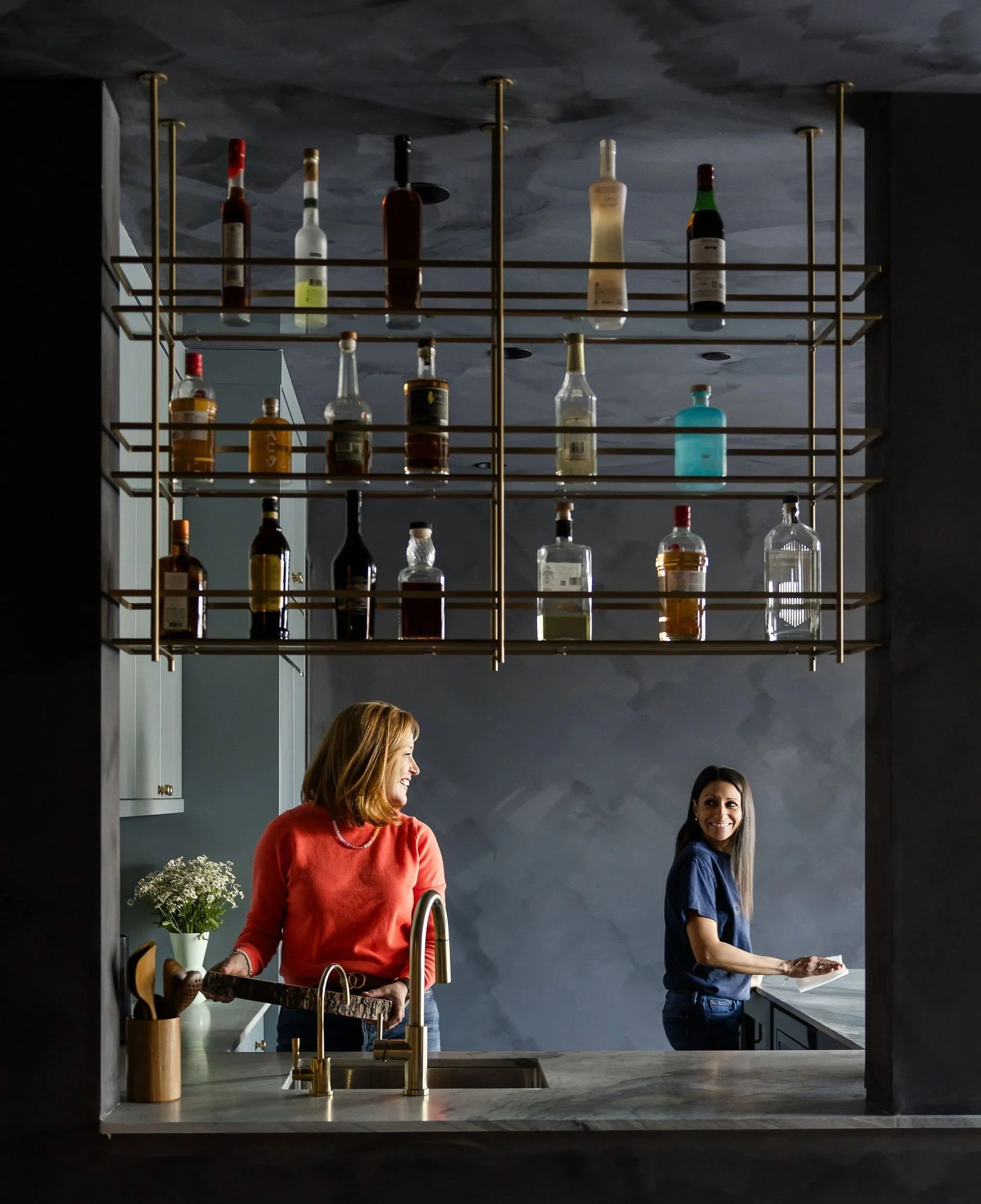 Ashley and another team member organizing a modern kitchen with a bar shelf featured