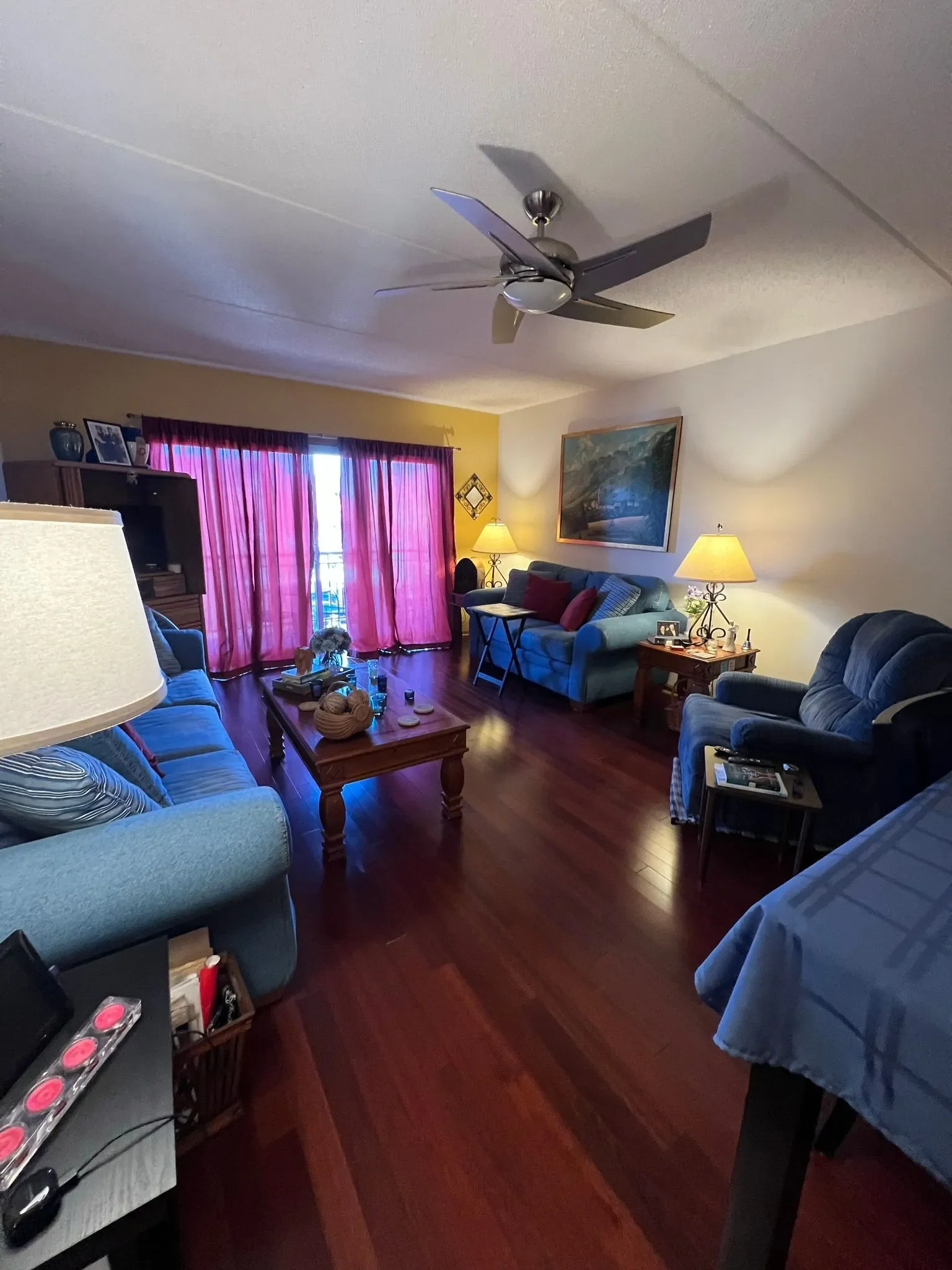 A "before" photo of a condo family room with dated furniture, dark wood tones, and traditional decor from the early 2000s.