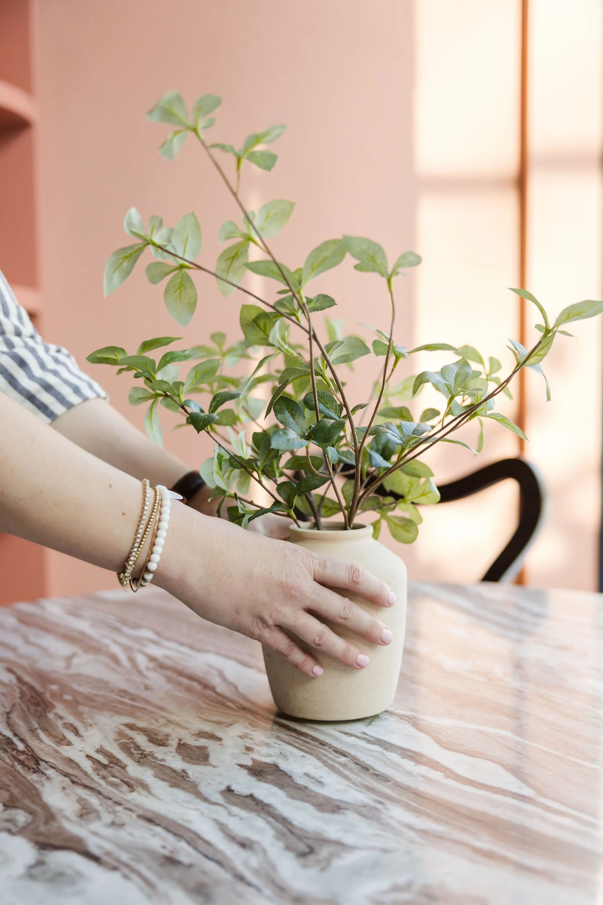 Ashely setting plant down on a marble table to stage an area of a home