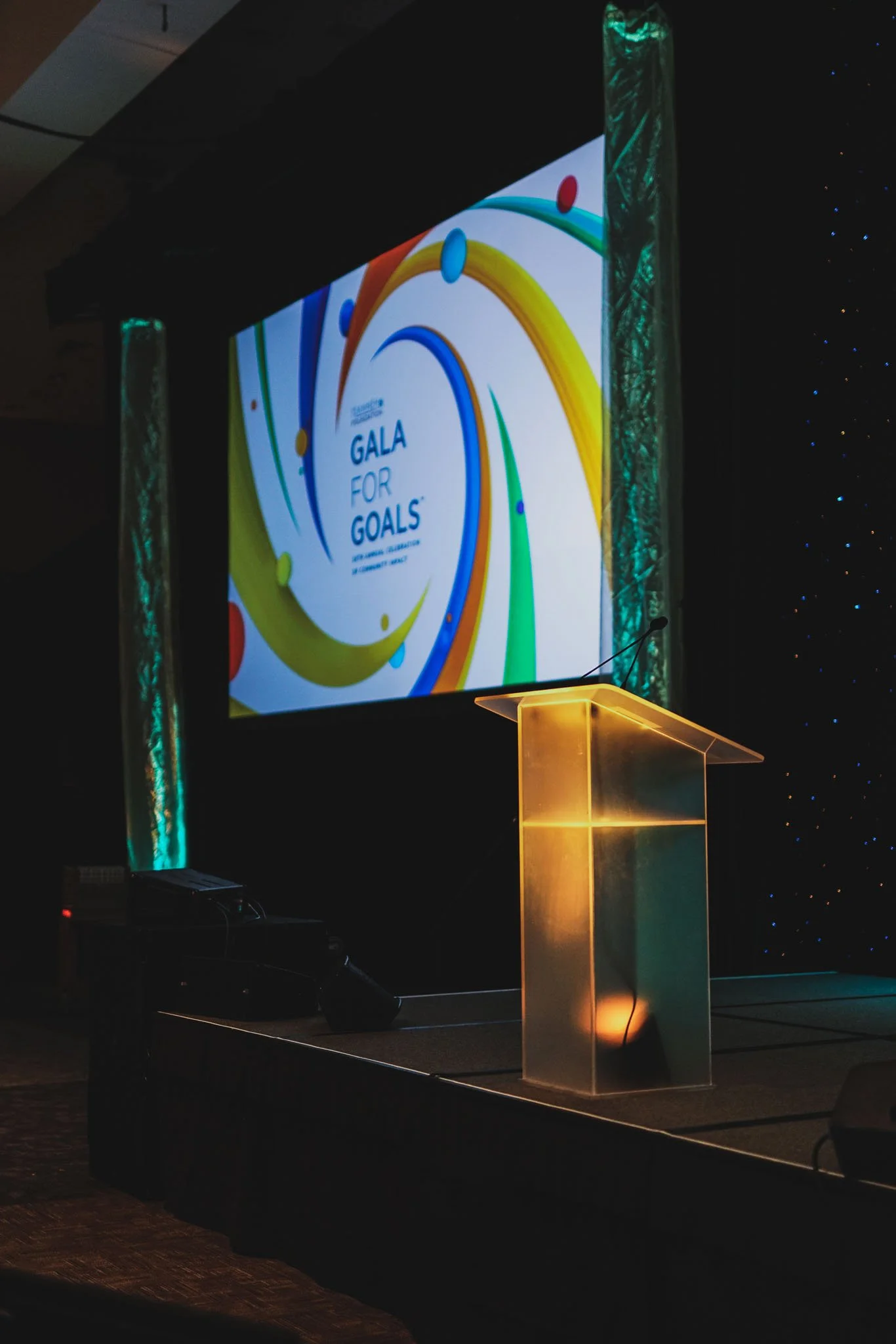 Stage setup at a conference with a large screen displaying 'GALA FOR GOALS', a transparent podium, and colorful abstract graphics.