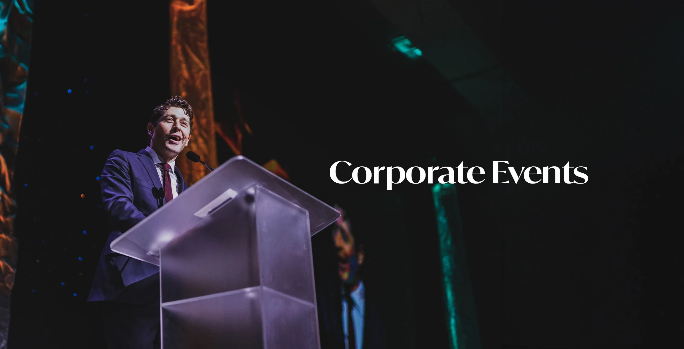 Man speaking at a podium during a corporate event, with the words 'Corporate Events' overlayed on the right side of the image.