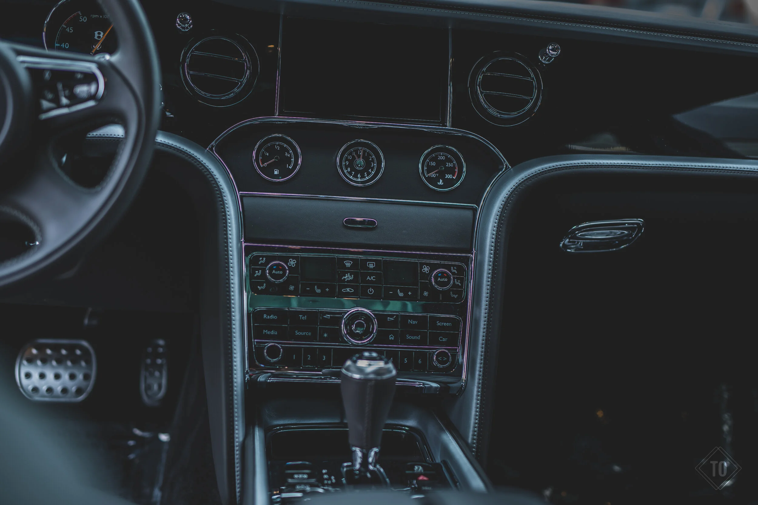 Interior of a luxury car dashboard with digital and analog gauges, climate controls, and infotainment system.