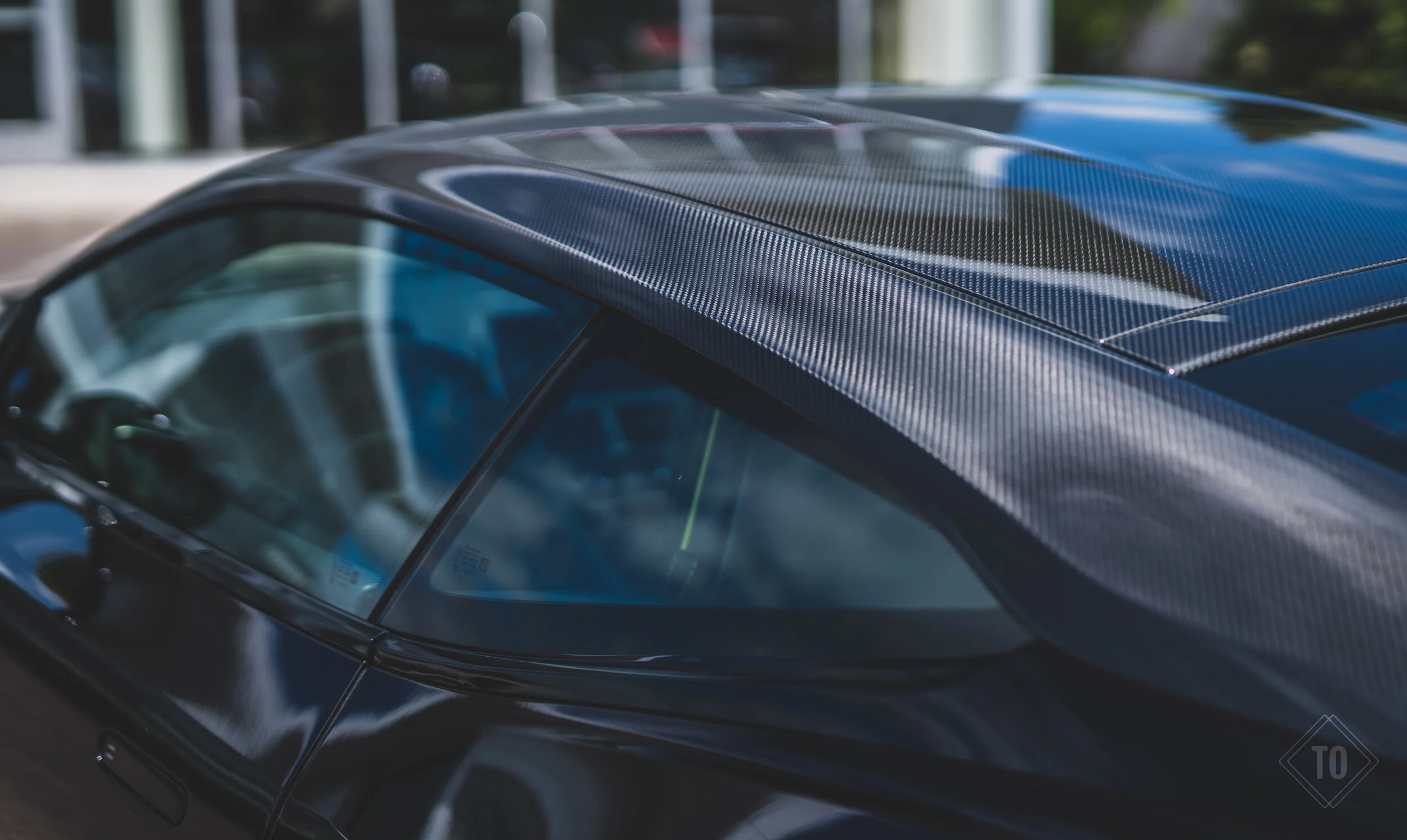 Close-up of a black sports car with a carbon fiber roof and windshield.