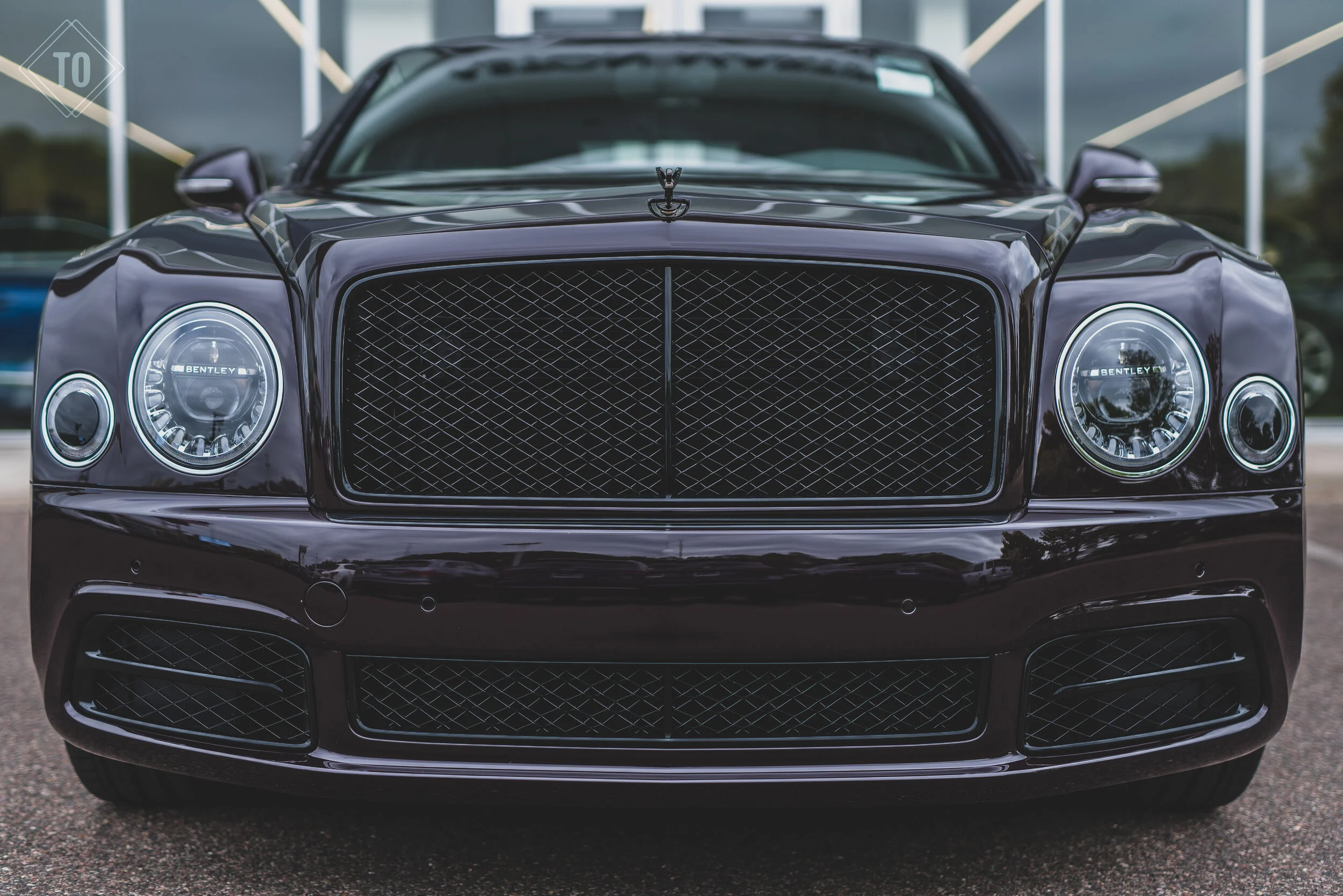 Front view of a black luxury Bentley car with a prominent grille and headlight design.
