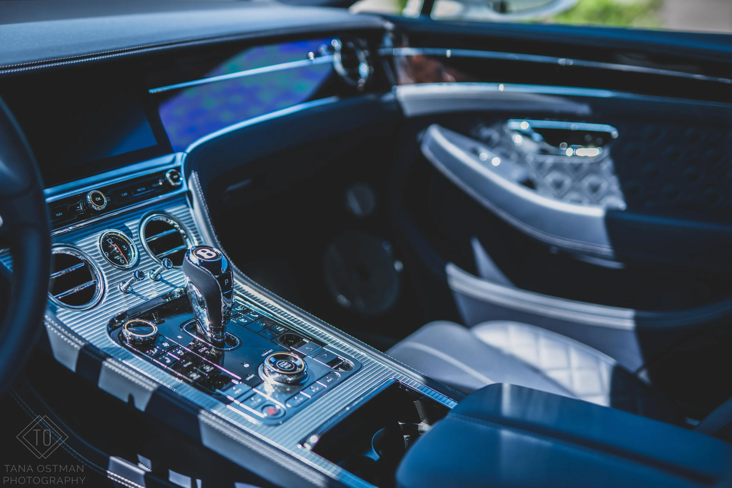 Interior of a luxury car featuring a sleek dashboard with a prominent gear shifter, multiple control buttons, and digital displays.