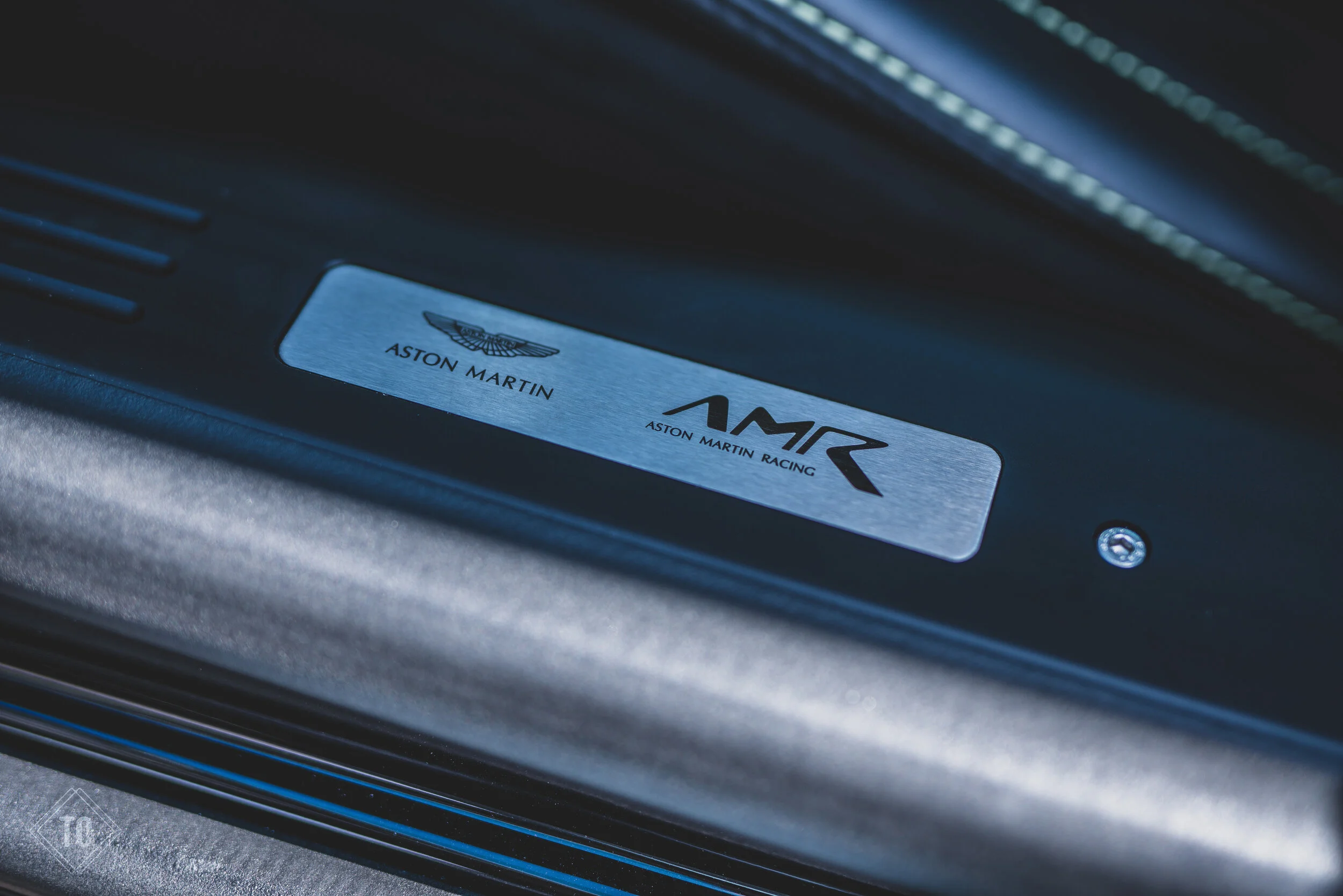 Close-up of an Aston Martin logo and racing badge on a vehicle interior or component.