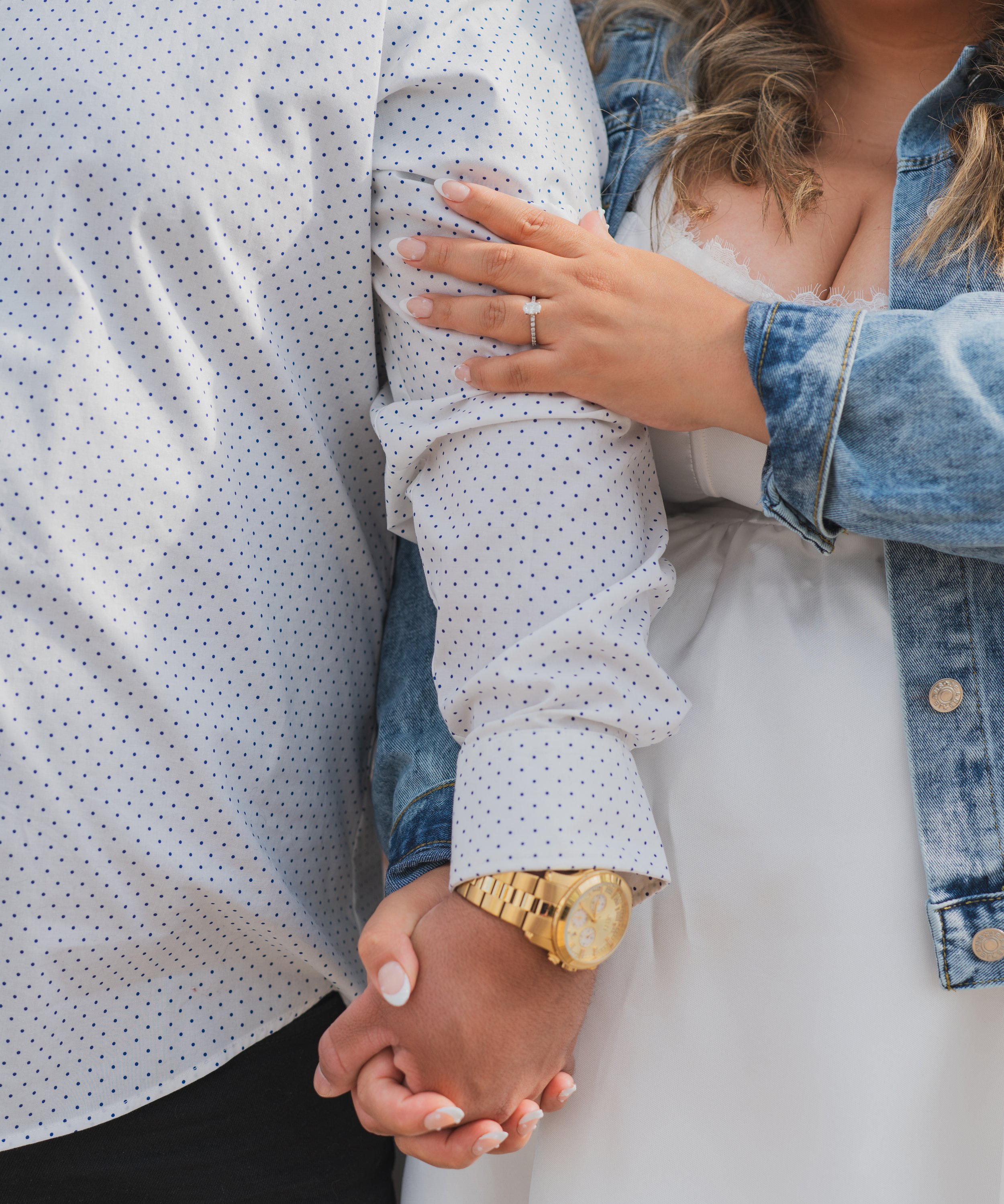 A woman with a wedding ring and a gold watch holds a man's hand, showing an intimate moment.
