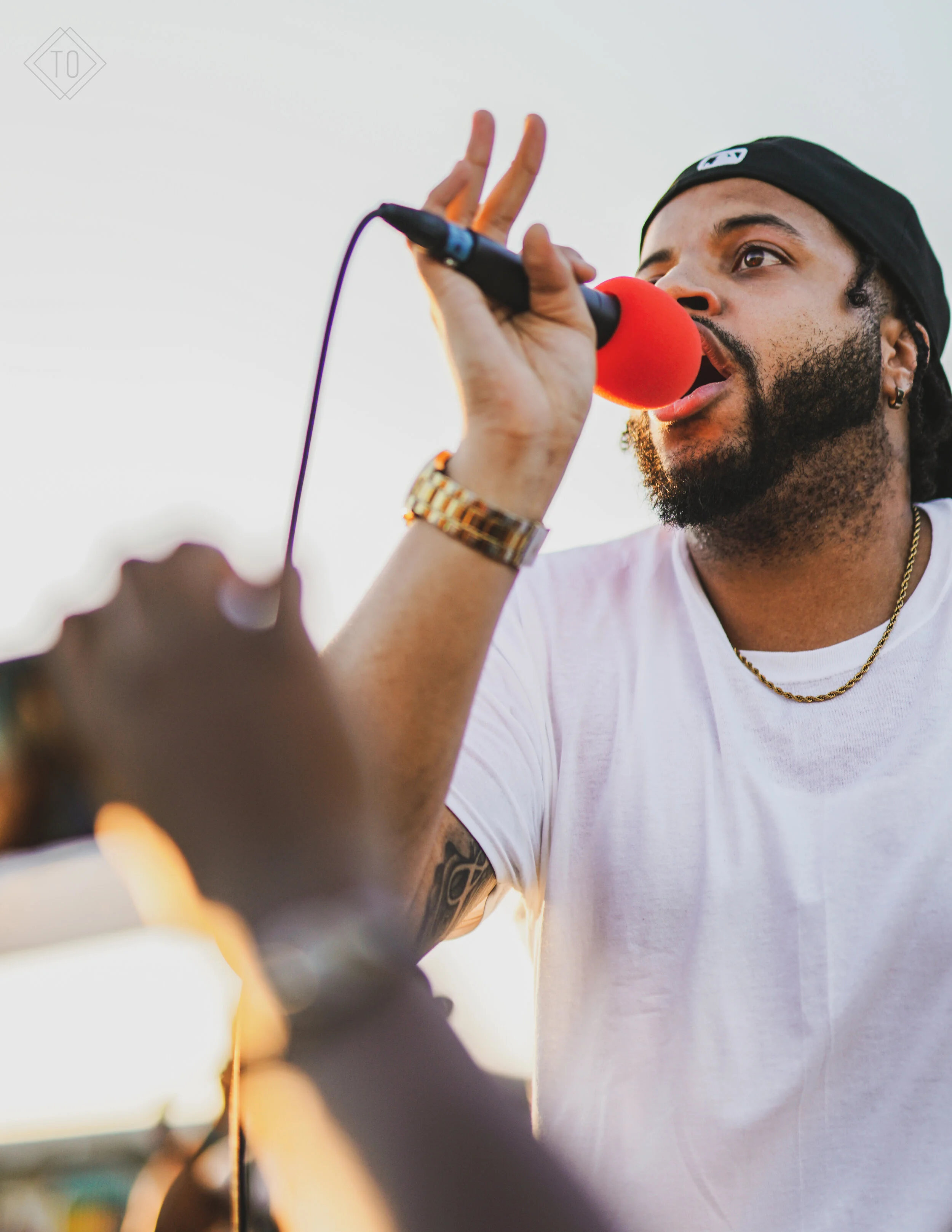 A man holding a microphone with a red foam cover, singing or speaking into it.