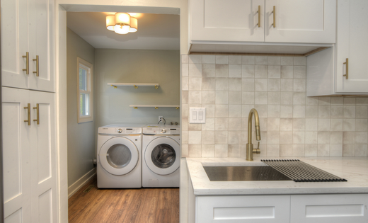 Renovated laundry room with washer and dryer, built-in shelves, and wood floor