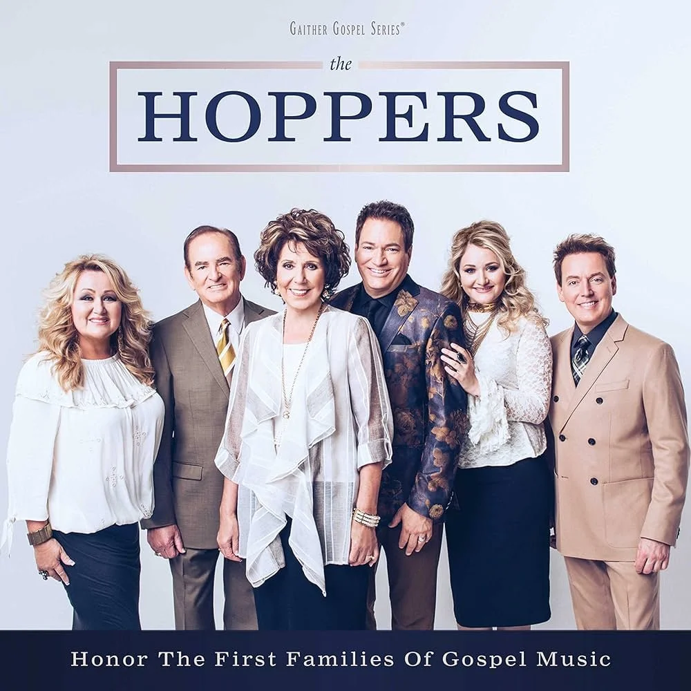 Cover of a music album titled "The Hoppers" featuring seven smiling people in formal attire standing in a row against a light background, with the subtitle "Honor The First Families Of Gospel Music."