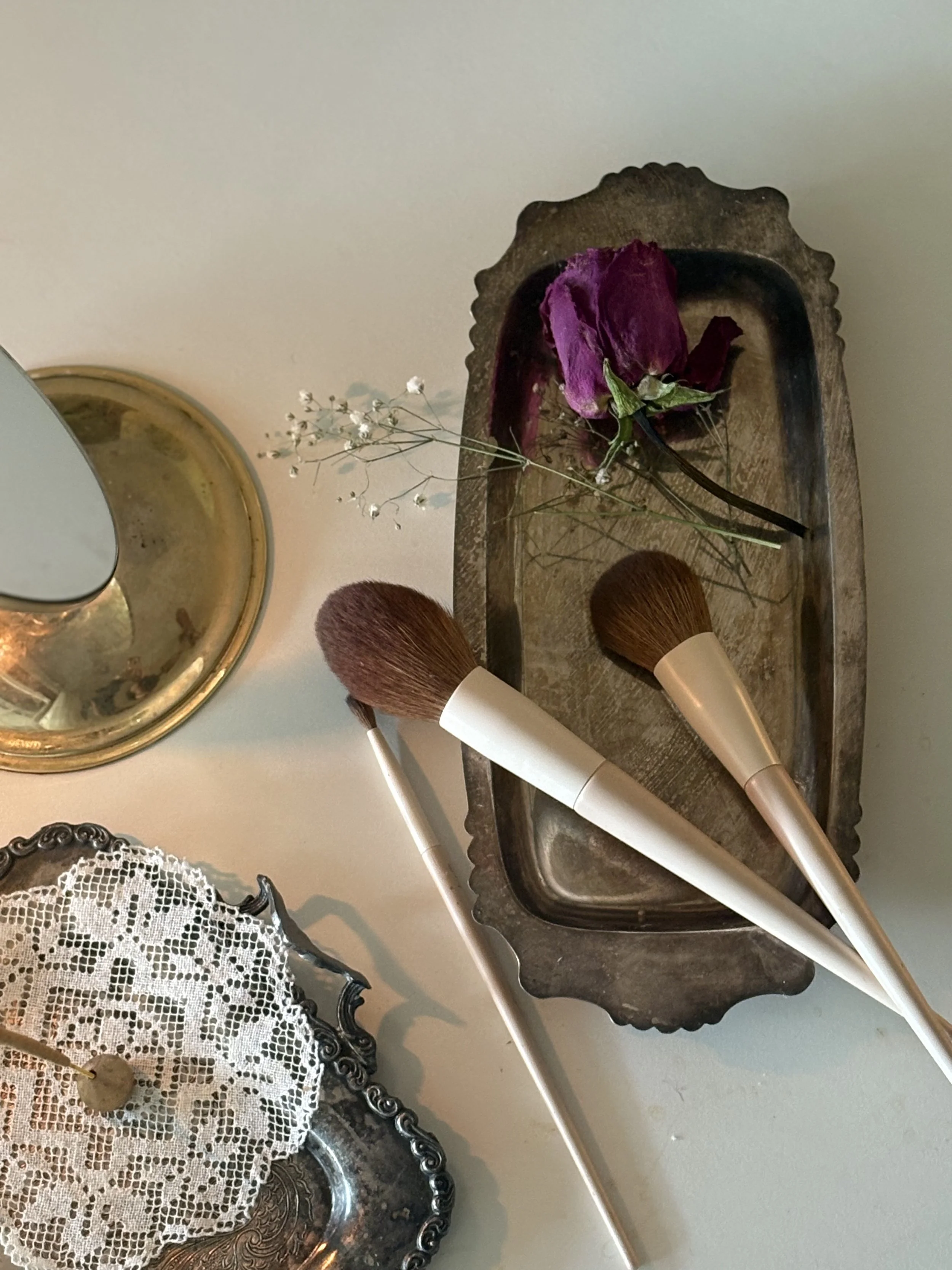 Vintage tray with dried flower bouquet and makeup brushes.