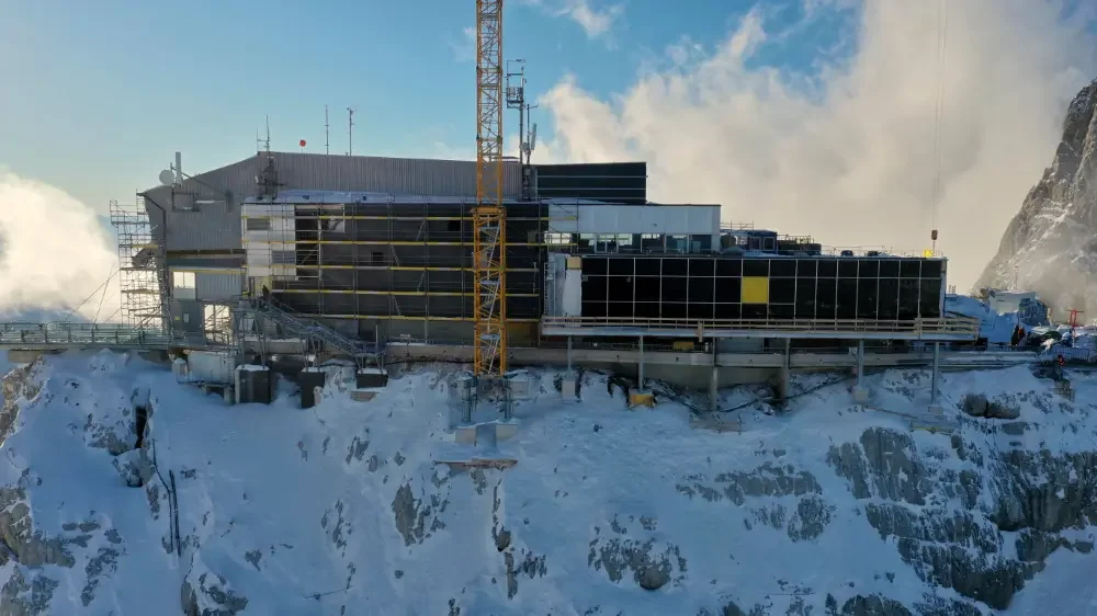 Bauarbeiten an einer modernen, abgelegenen Bergstation im Schnee mit Baukran