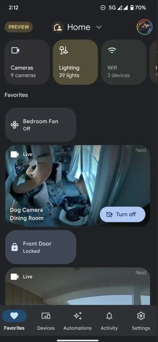 Smartphone screen displaying a home automation app with icons for cameras, lighting, Wi-Fi, and door lock, showing a live feed of dogs in the dining room.