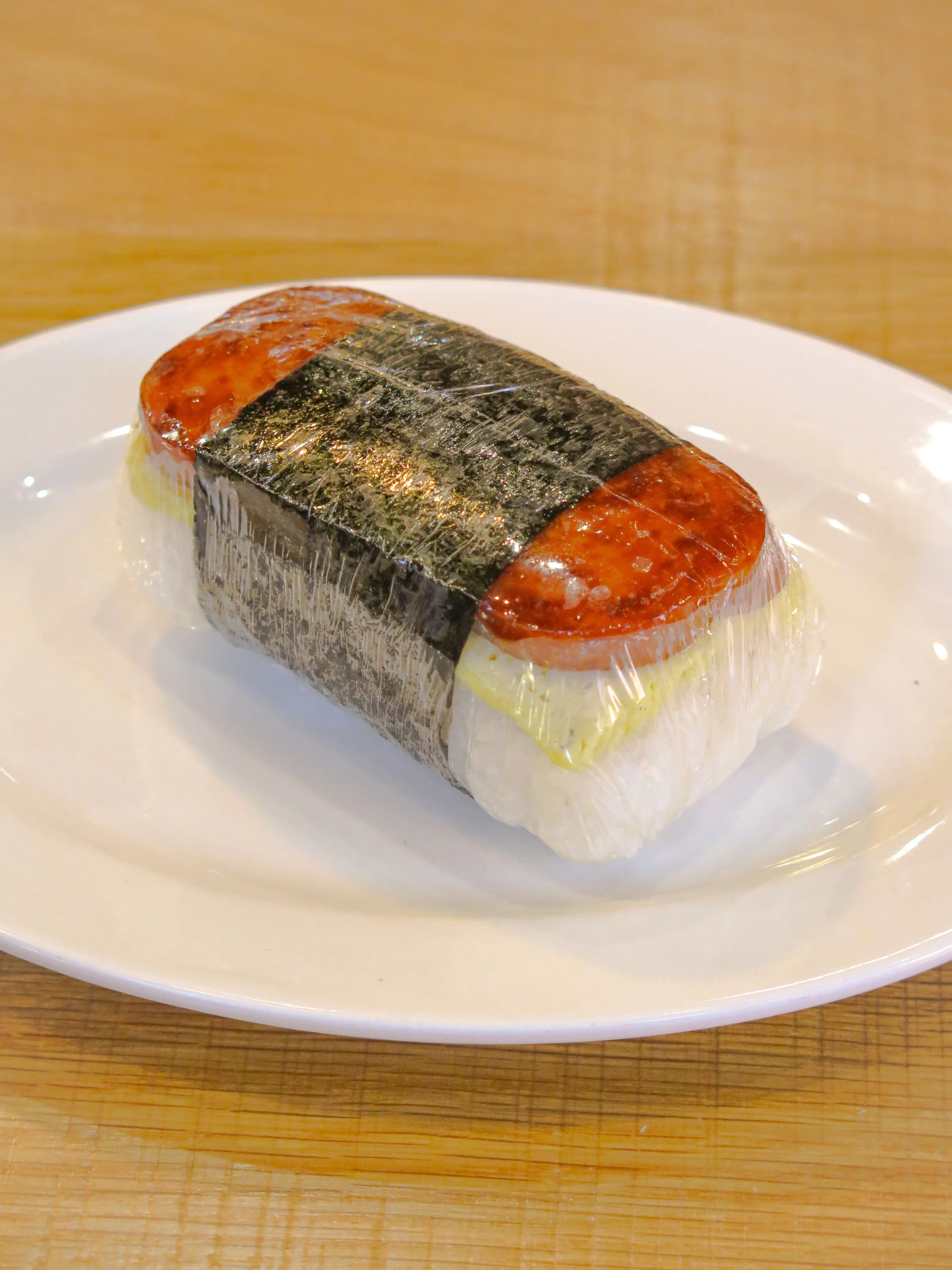 A plate with a piece of sushi wrapped in seaweed, containing fish, rice, and other ingredients.