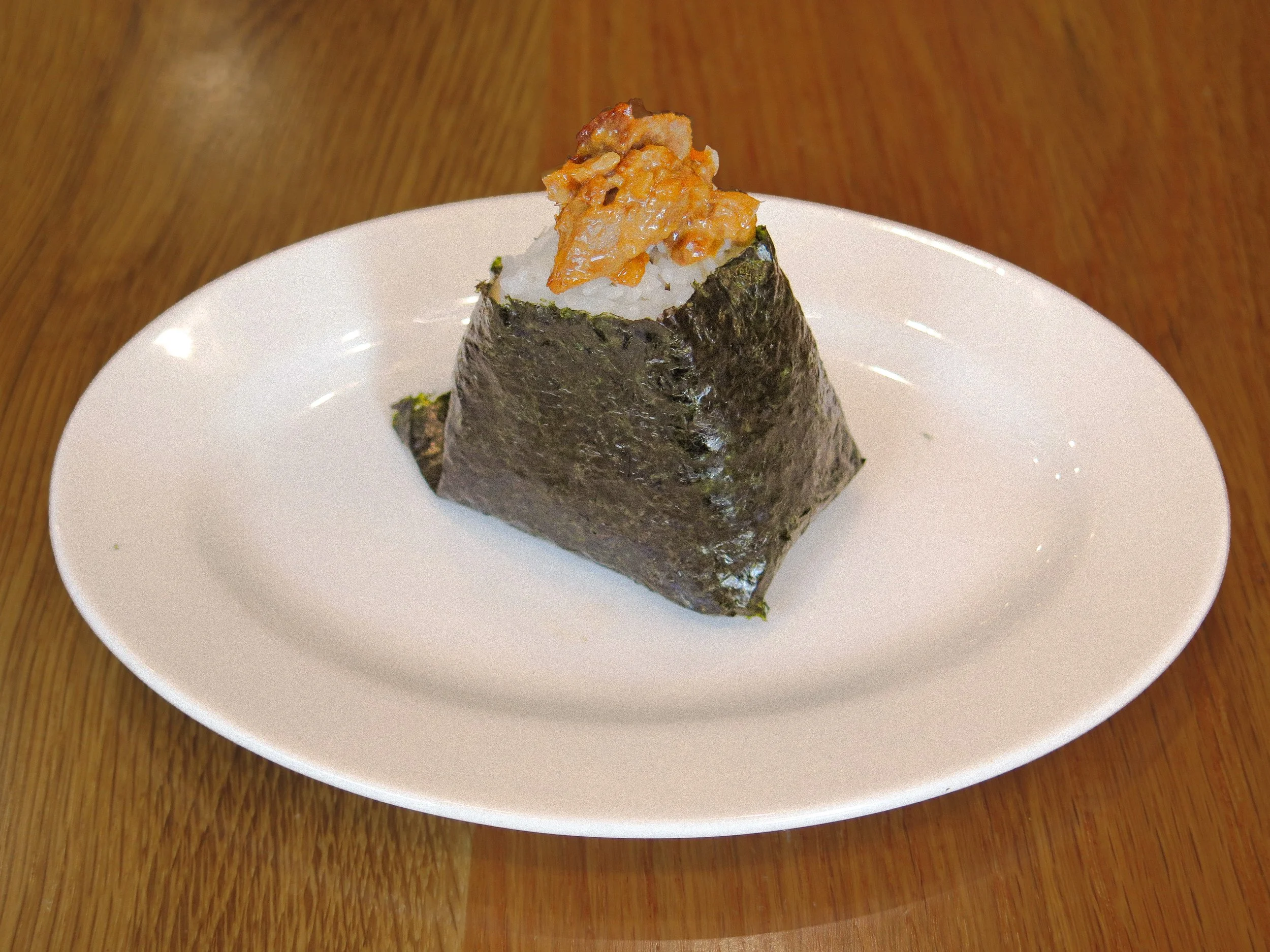 A piece of onigiri rice ball with seaweed wrapping, topped with fish roe