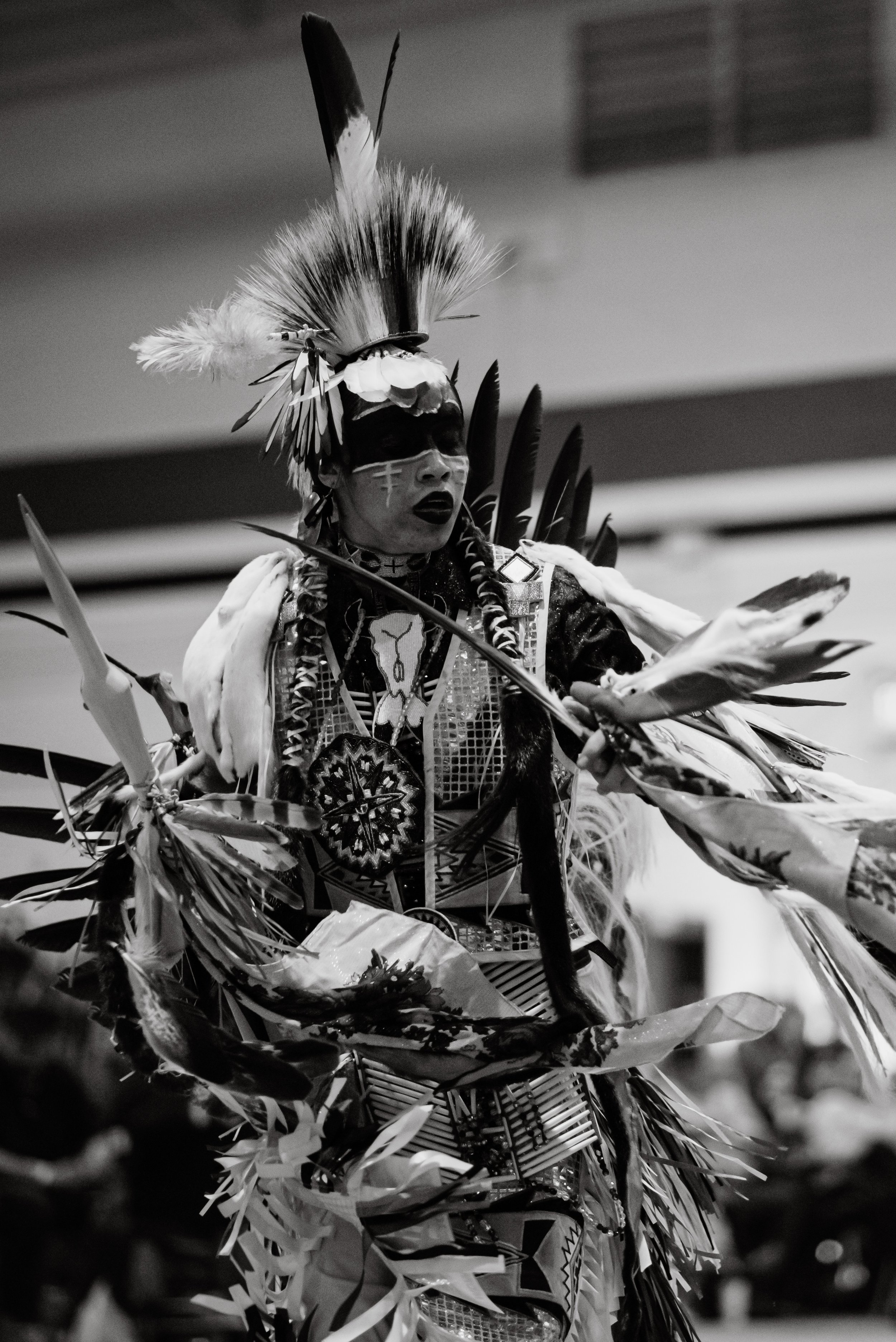 A person dressed in traditional Native American regalia, including feathers, beads, and intricate fabric, participating in a cultural event or ceremony.