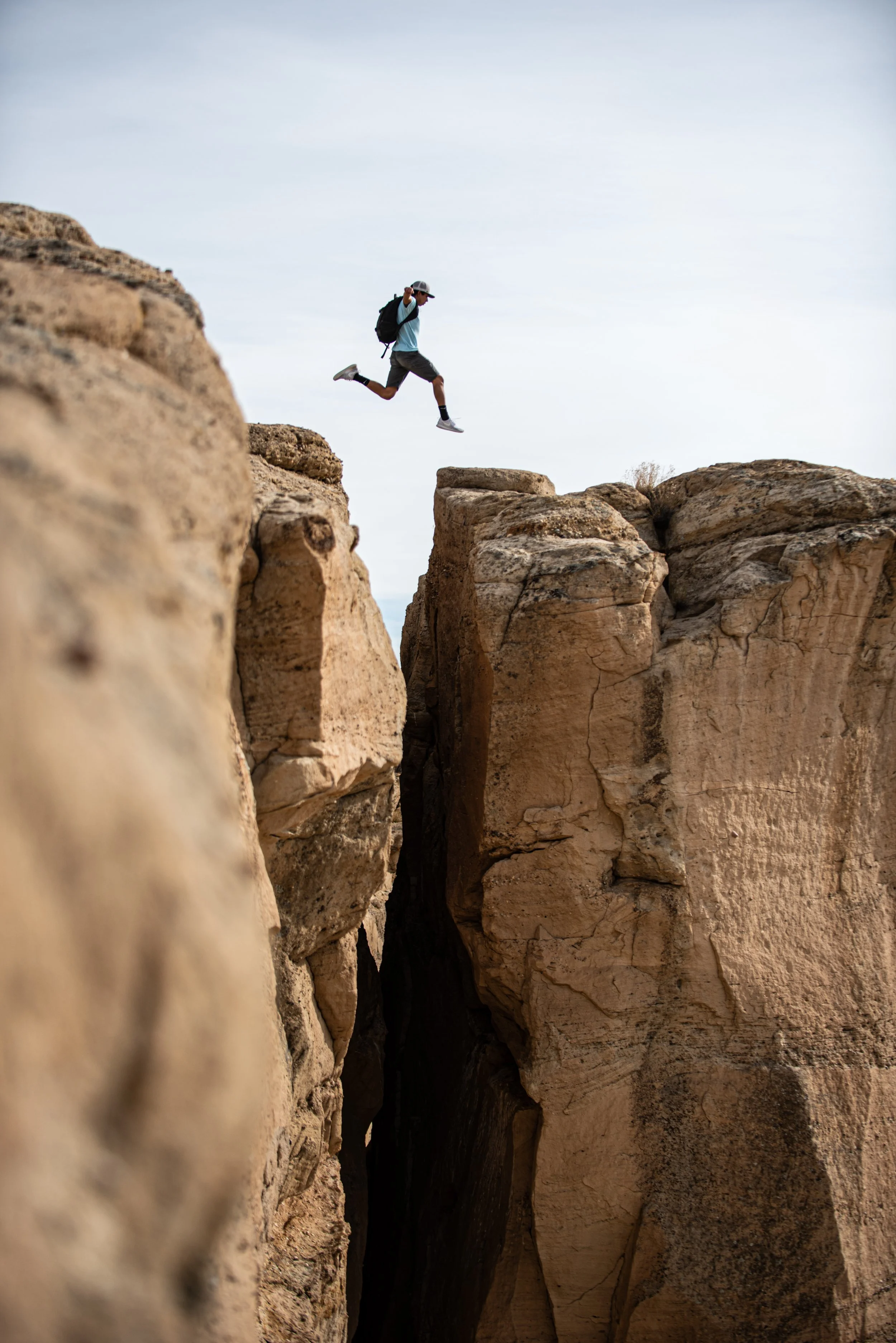 A person jumping between large rocks in a desert landscape.