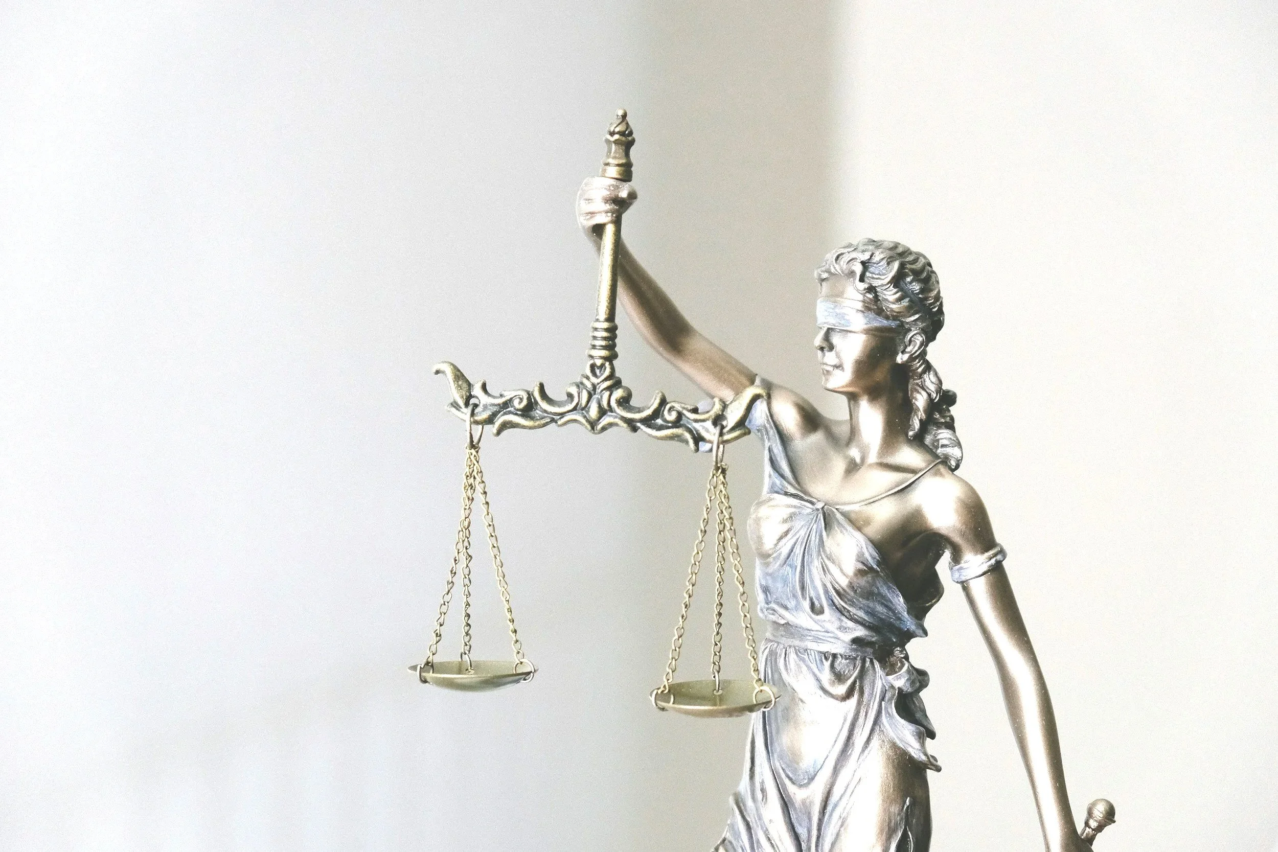 A metallic statue of Lady Justice holding a balance scale, with a blindfold over her eyes, representing fairness and impartiality in the legal system. Criminal Defense. Justice. Attorney. Fresno. Tulare. Visalia. Madera.