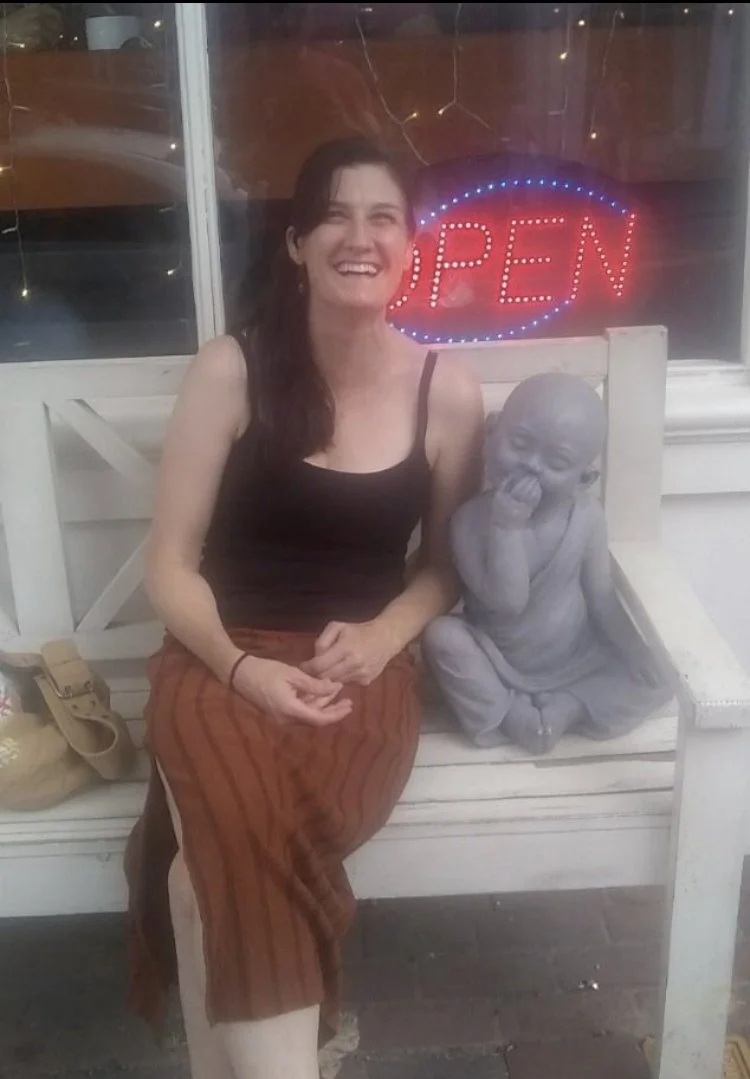 Photo of Evie sitting next to a baby Buddha statue