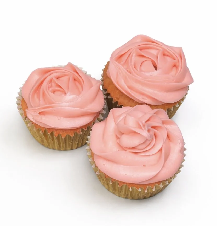 Three cupcakes with pink frosting swirled on top, placed on a white background.