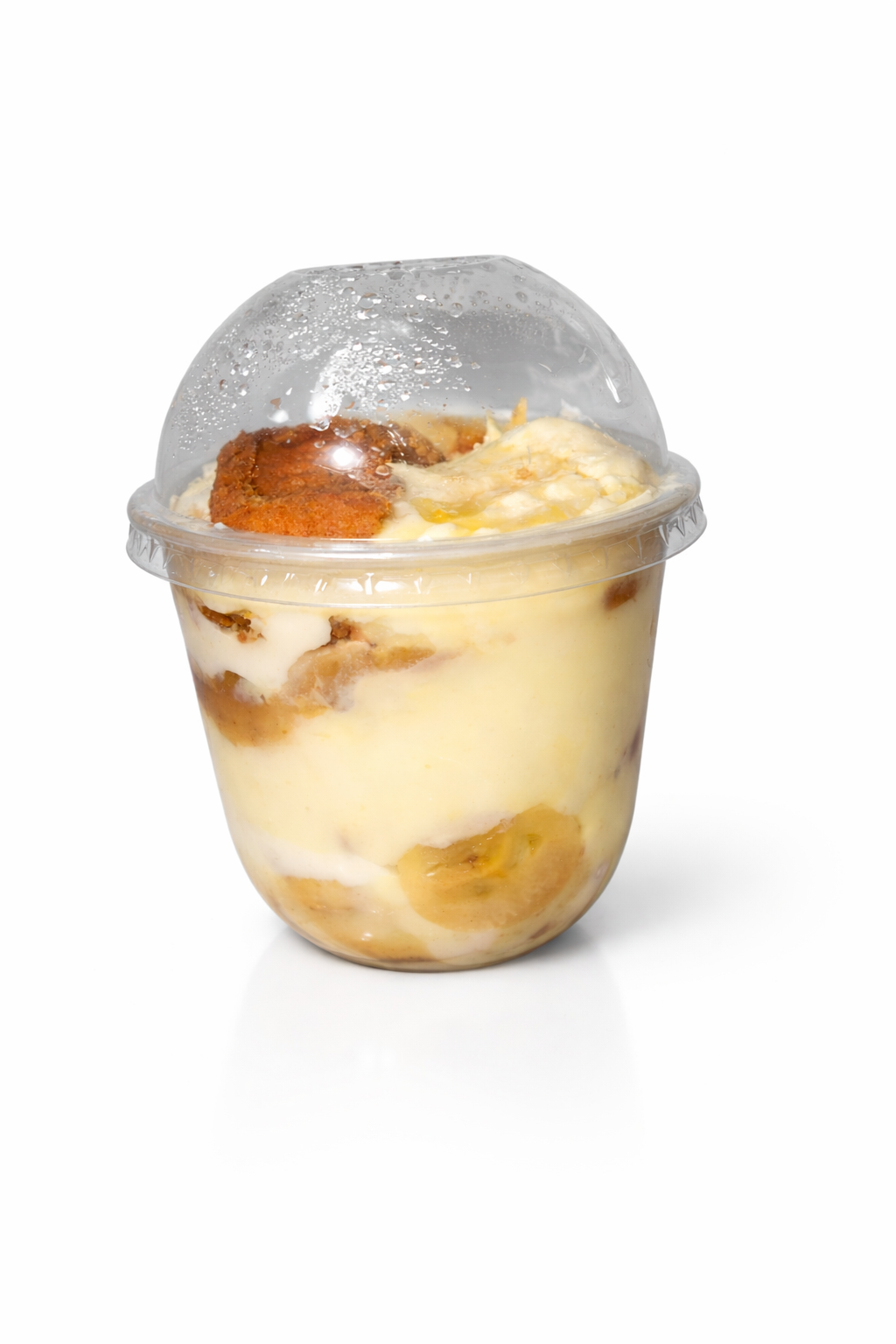 Biscoff Banana Pudding Dessert in a clear plastic cup with a dome lid, containing layers of banana slices, pudding, cheesecake filling and biscoff cookie pieces