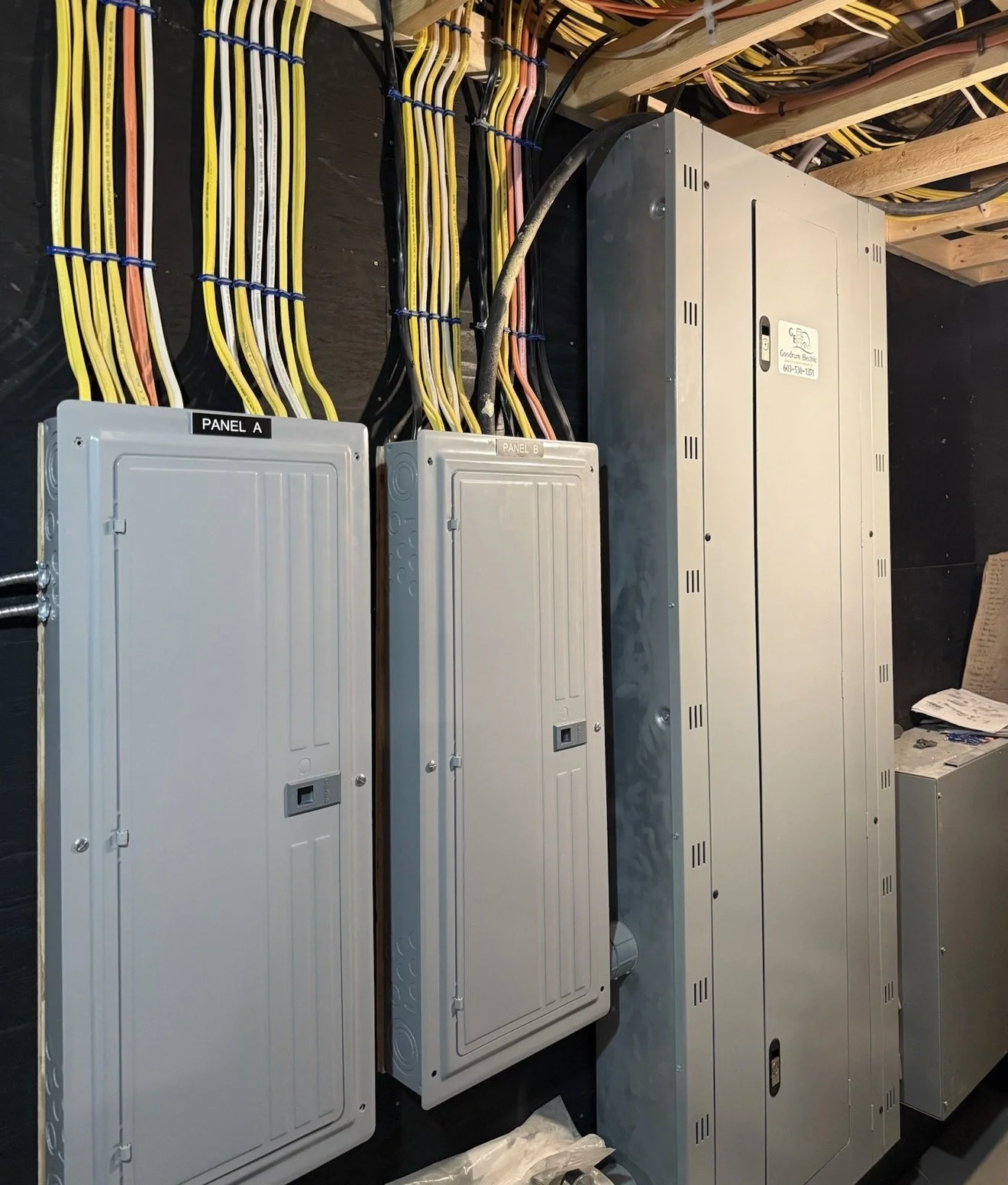 Electrical panels and wiring behind a wall, labeled Panel A and Panel B, with various colored wires organized and connected to the panels.