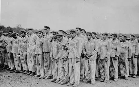 Prisoners clad in striped uniforms stand in formation