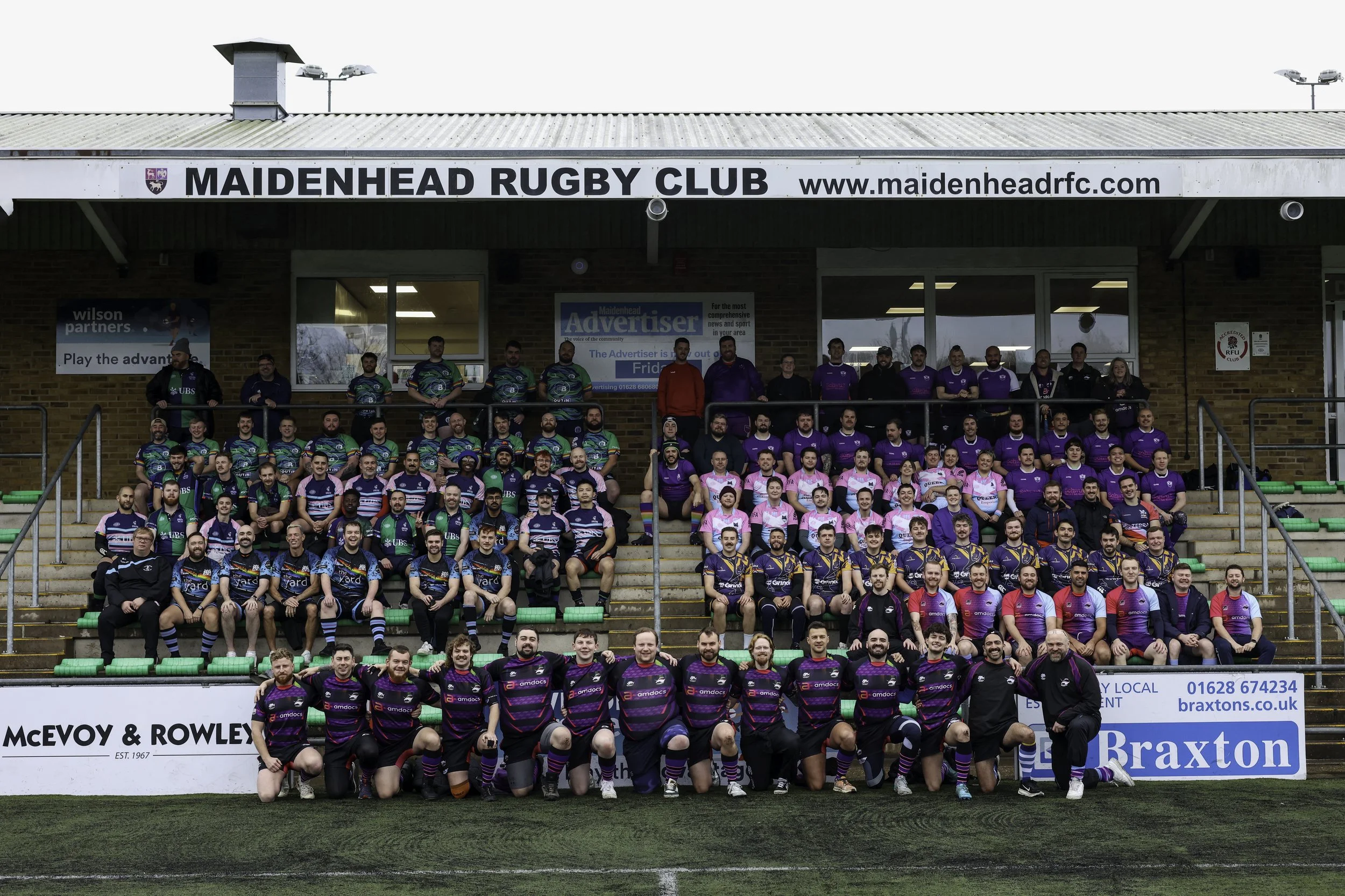 Group of rugby players posing on stadium steps in front of a sign for Maidenhead Rugby Club and sponsors.