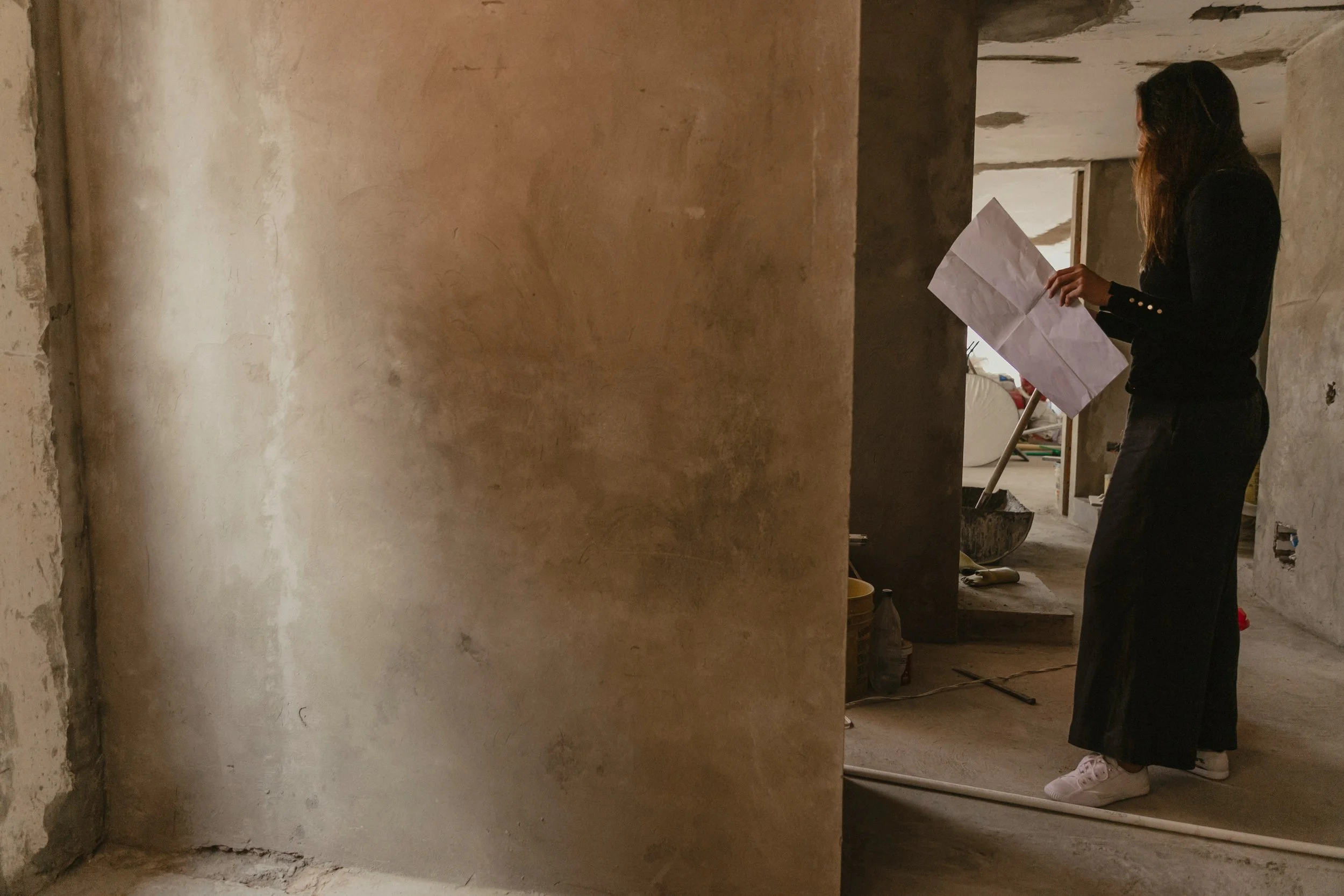 Woman with blueprint reviewing plans on construction site during a walk through.