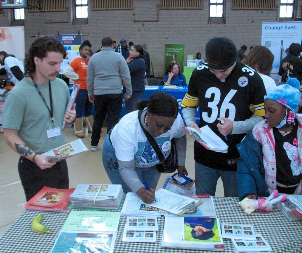 Volunteers sign up new volunteers at a literature table at a college