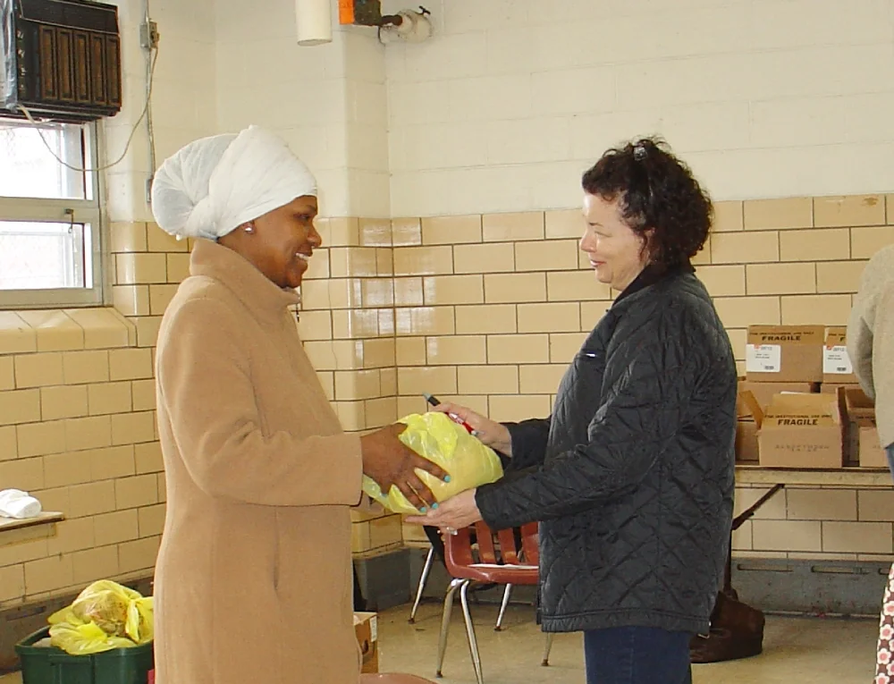 An ESWA volunteer hands a member a turkey for Thanksgiving 