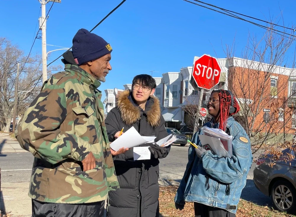Two ESWA volunteers in winter clothing sign up a member on the street 