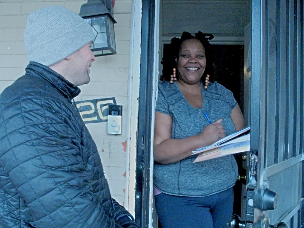 A canvass volunteer put a smile on the face of a new member as she signs up at her doorway