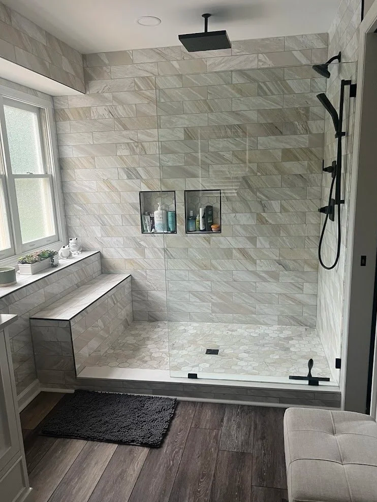 Custom walk-in shower with tile walls, custom bench, and black fixtures for a bathroom renovation