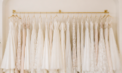 A row of white wedding dresses hanging on a gold clothing rack.