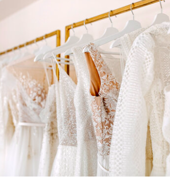 A row of white wedding dresses hanging on a gold clothing rack.