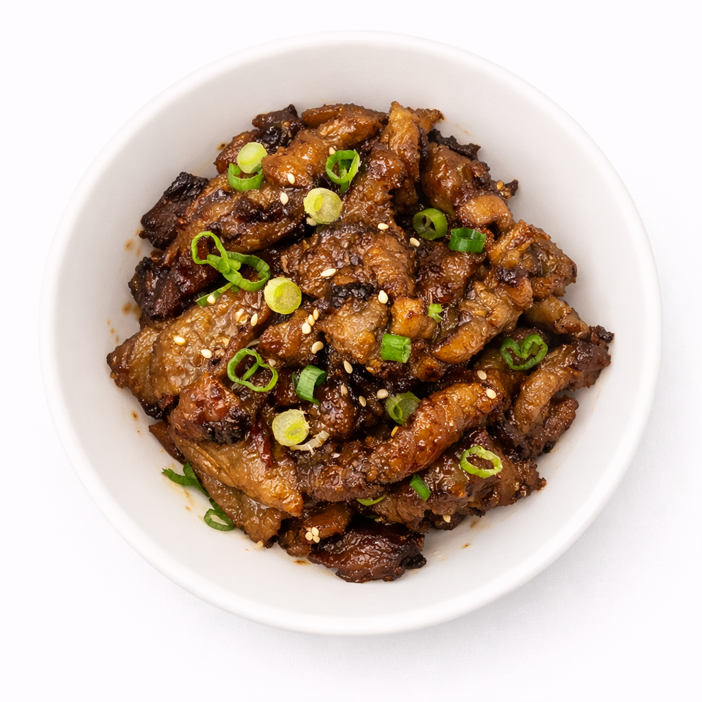 Dish of cooked eggplant garnished with chopped green onions and sesame seeds in a white bowl