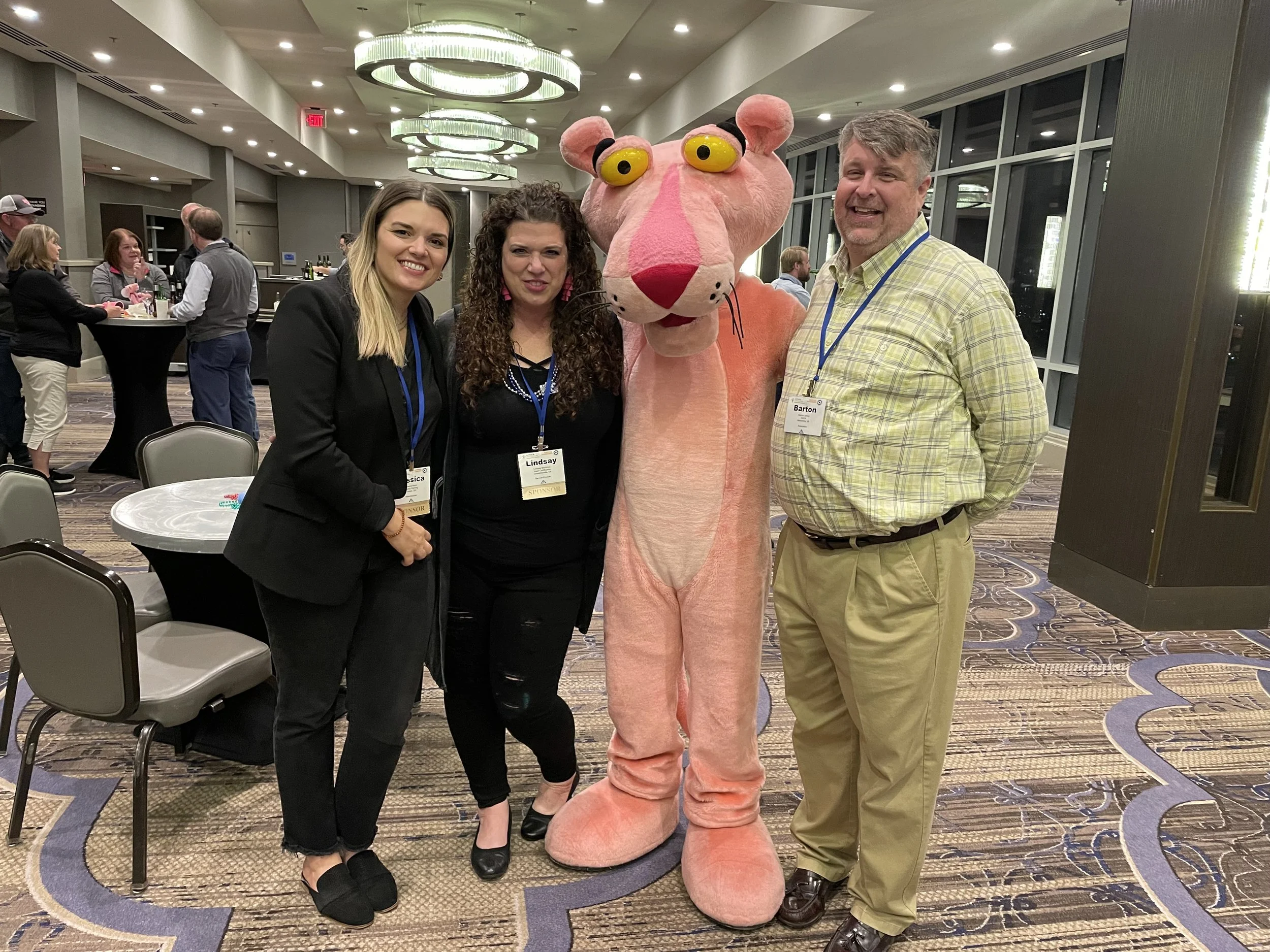 Owens Corning Aircare™ Rep, Executive Director of Air Conditioning Contractors of America, and Emberfly's founder, Lindsay Bachman, all stand with the iconic Owens Corning Pink Panther at a co-sponsored happy hour at the ACCA national conference.