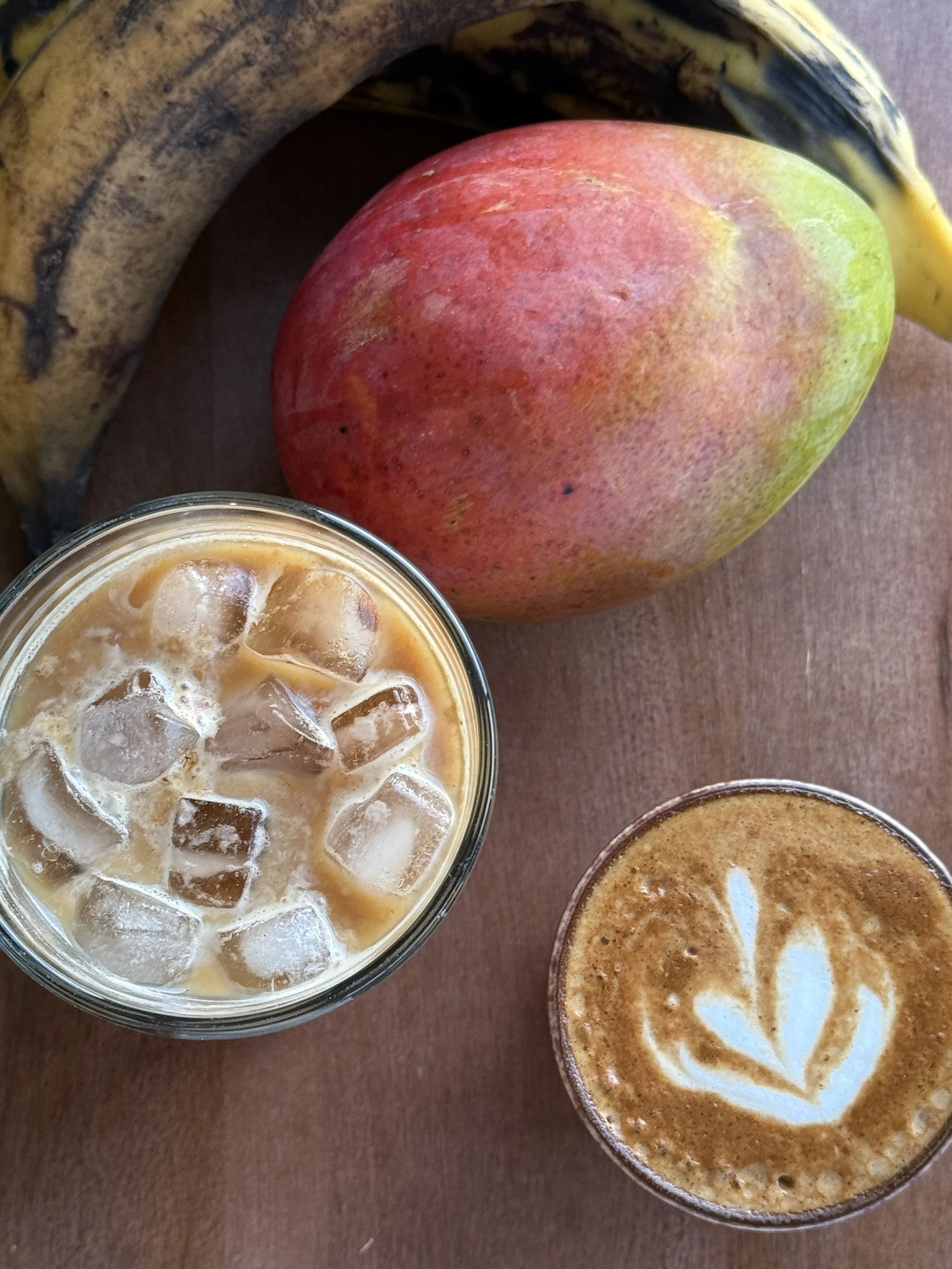 Images of a banana, an apple, and two iced coffee drinks on a wooden surface.