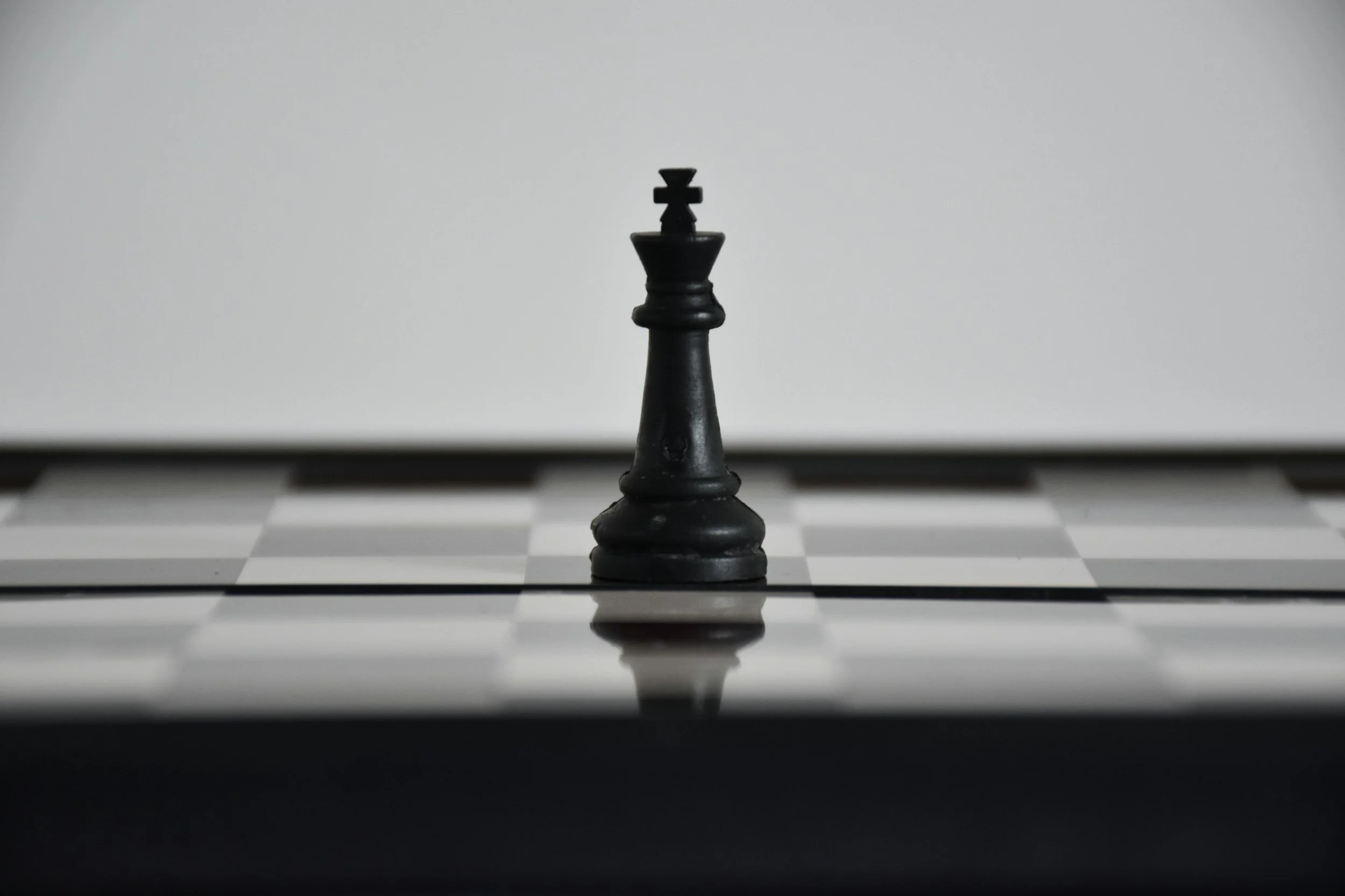A black king chess piece on a black and white checkerboard chessboard.