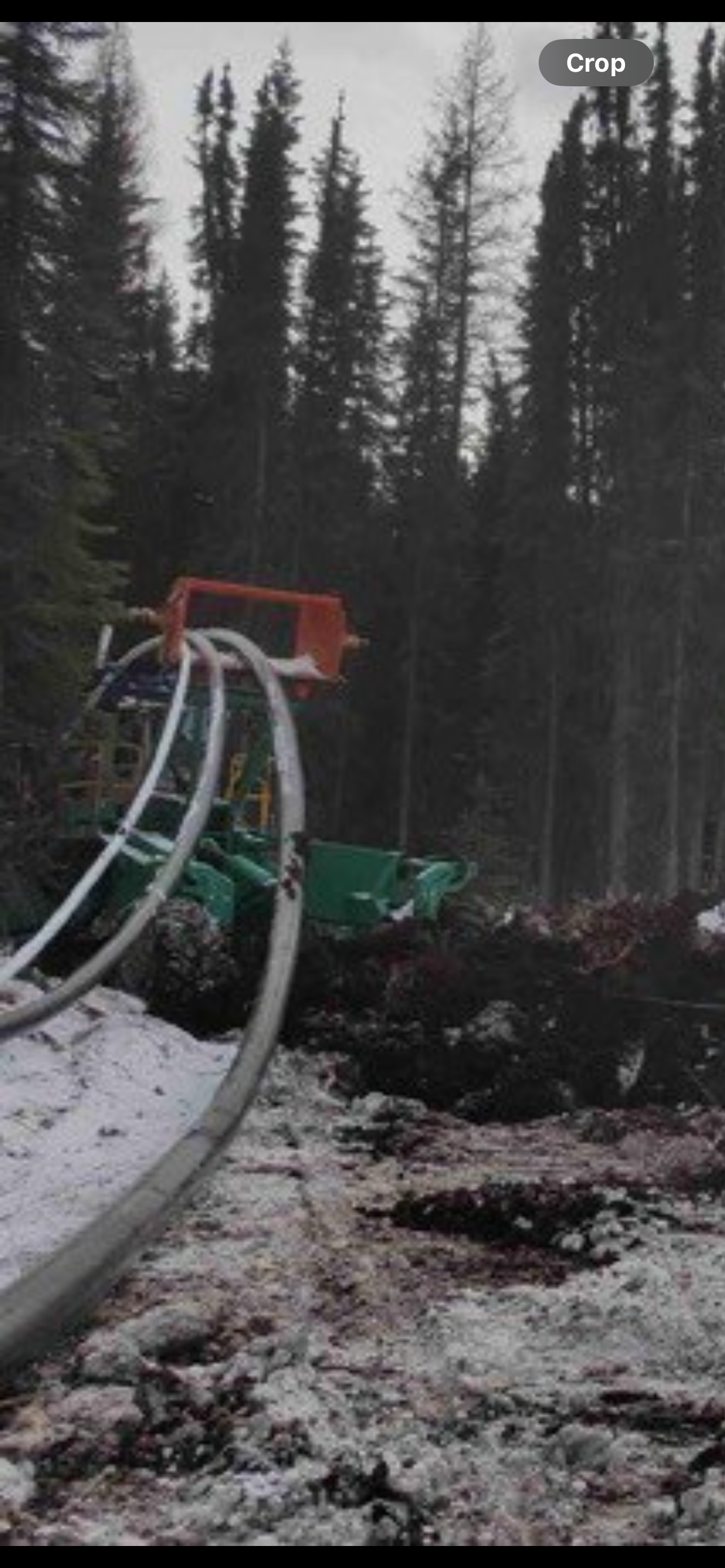 Firefighting equipment with hoses and a green tank on snowy ground in a forested area.