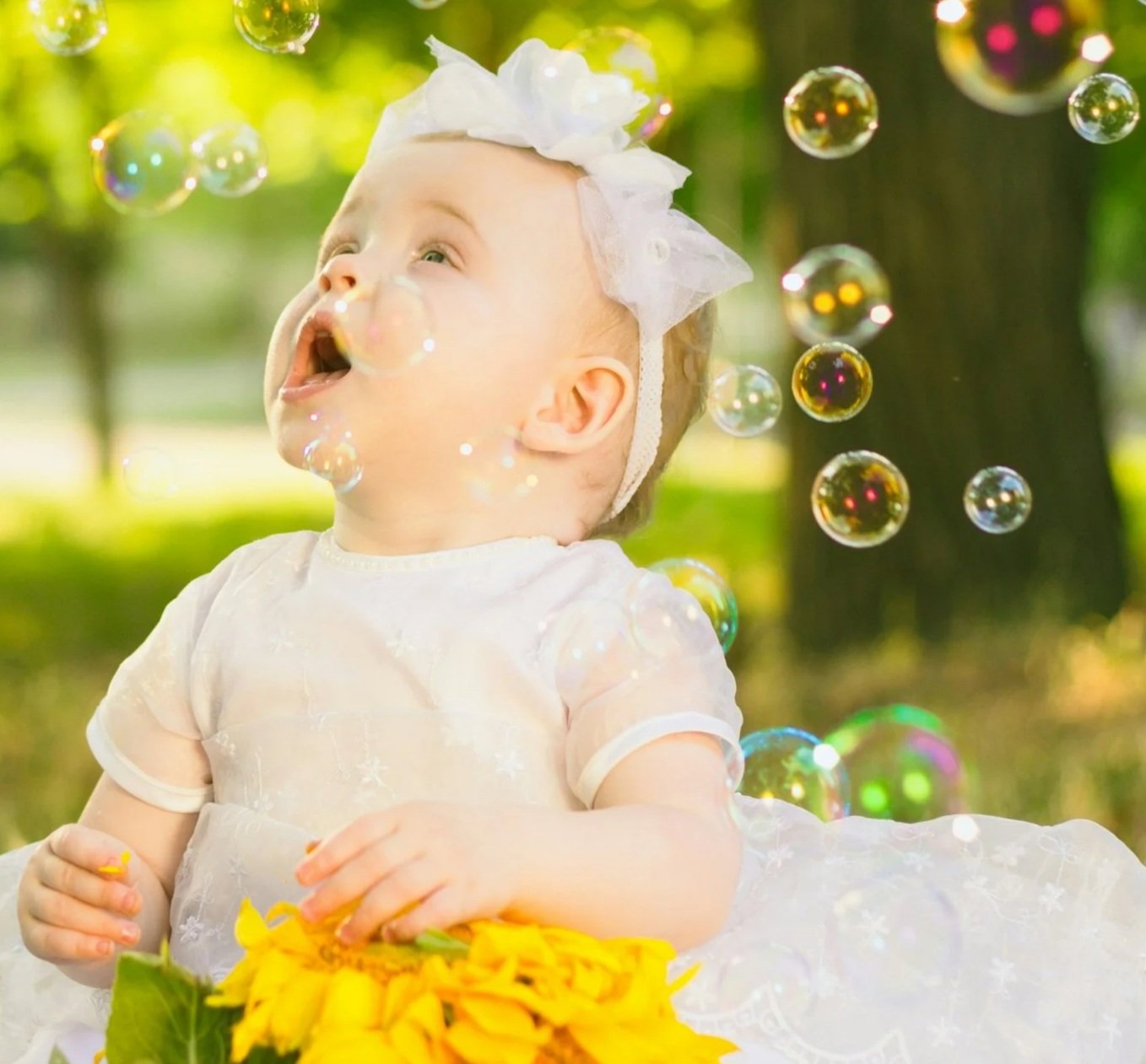 Baby looking up at bubbles with bow in hair